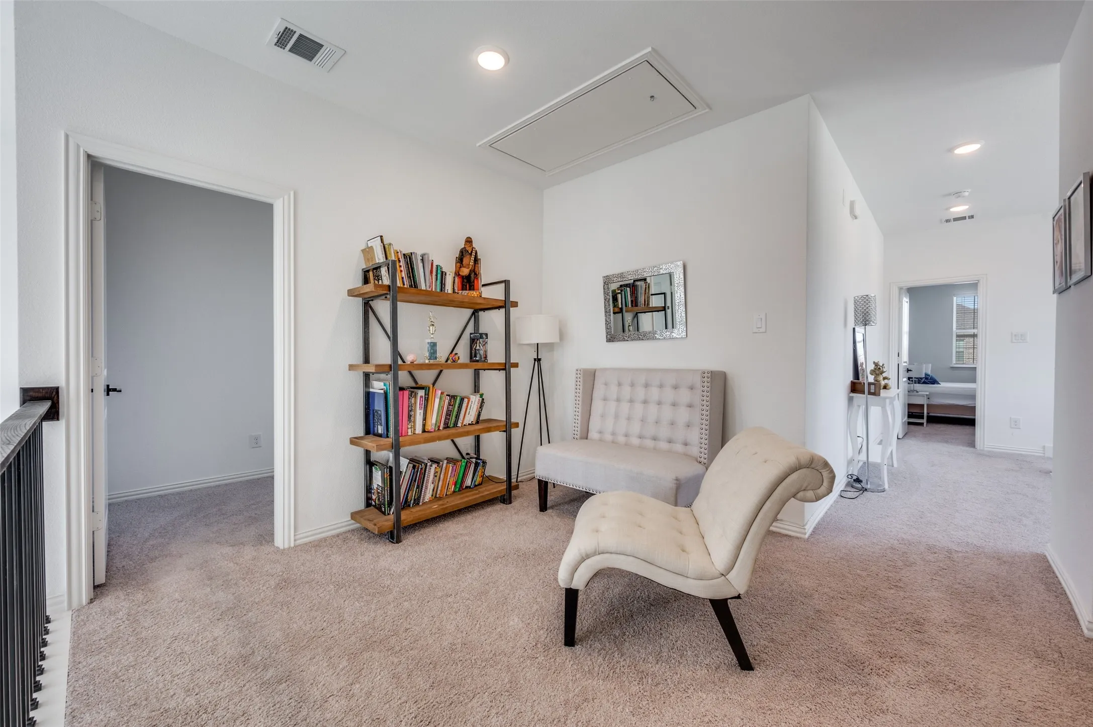 Carpeted landing area featuring recessed lighting, a white painted railing with black balusters, and a ceiling-mounted access panel