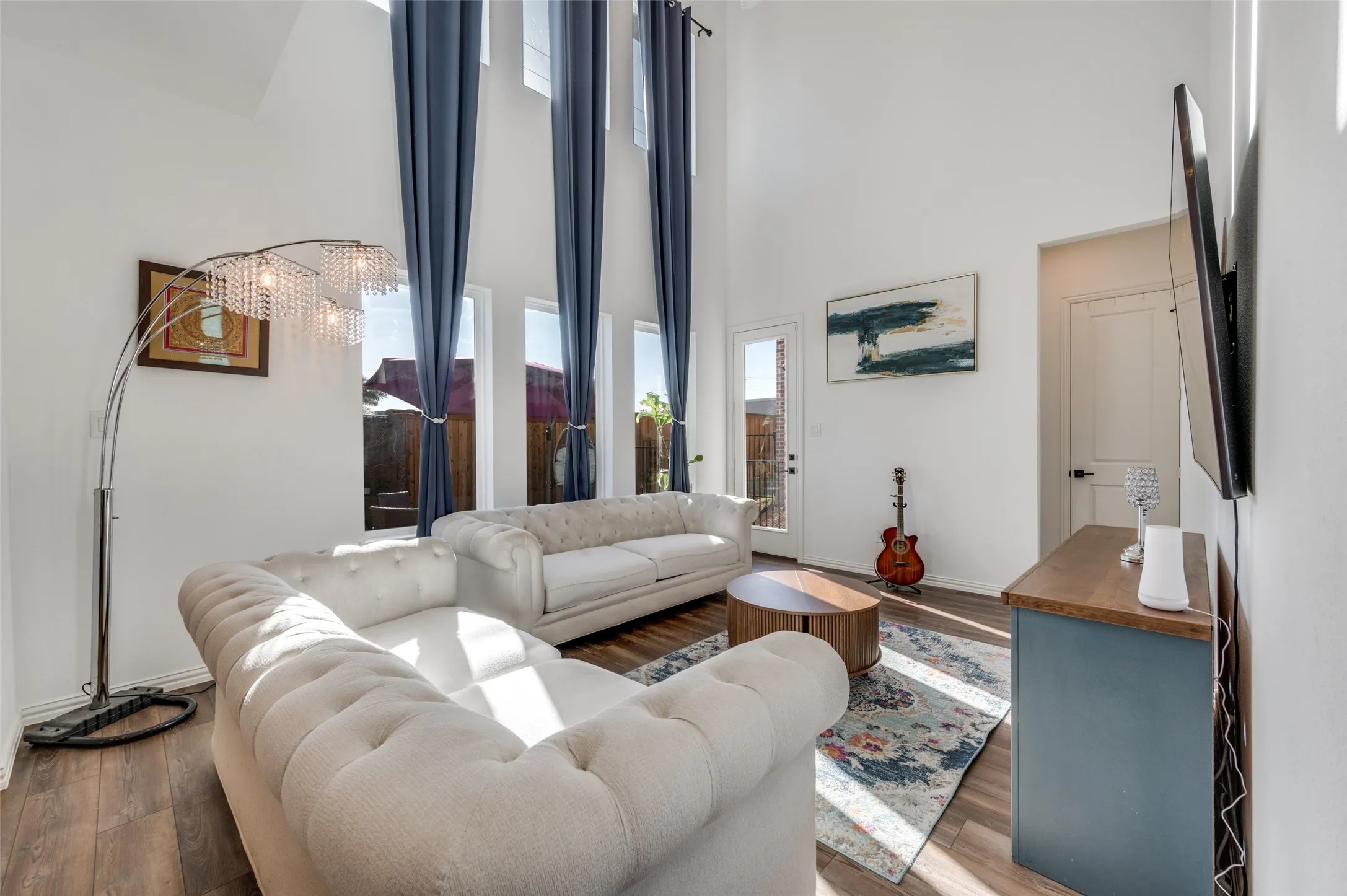 Vaulted ceiling with high windows, wood-finish flooring, and a glass-paneled exterior door