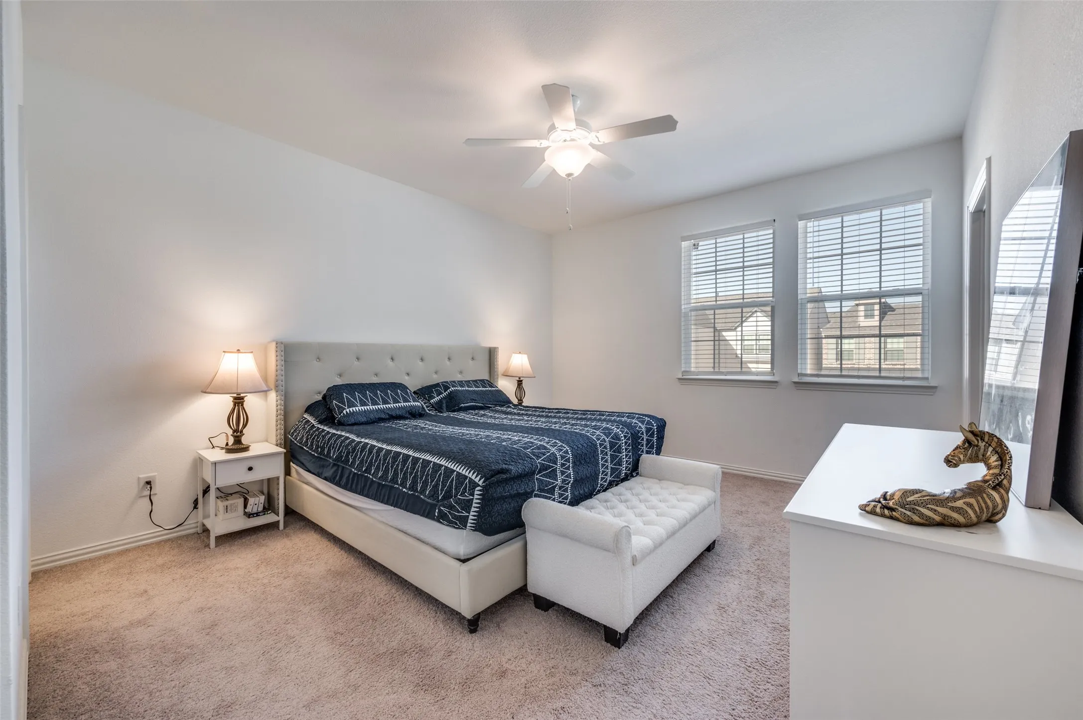 Carpeted flooring, dual windows with blinds, ceiling fan with light fixture, and neutral wall tones