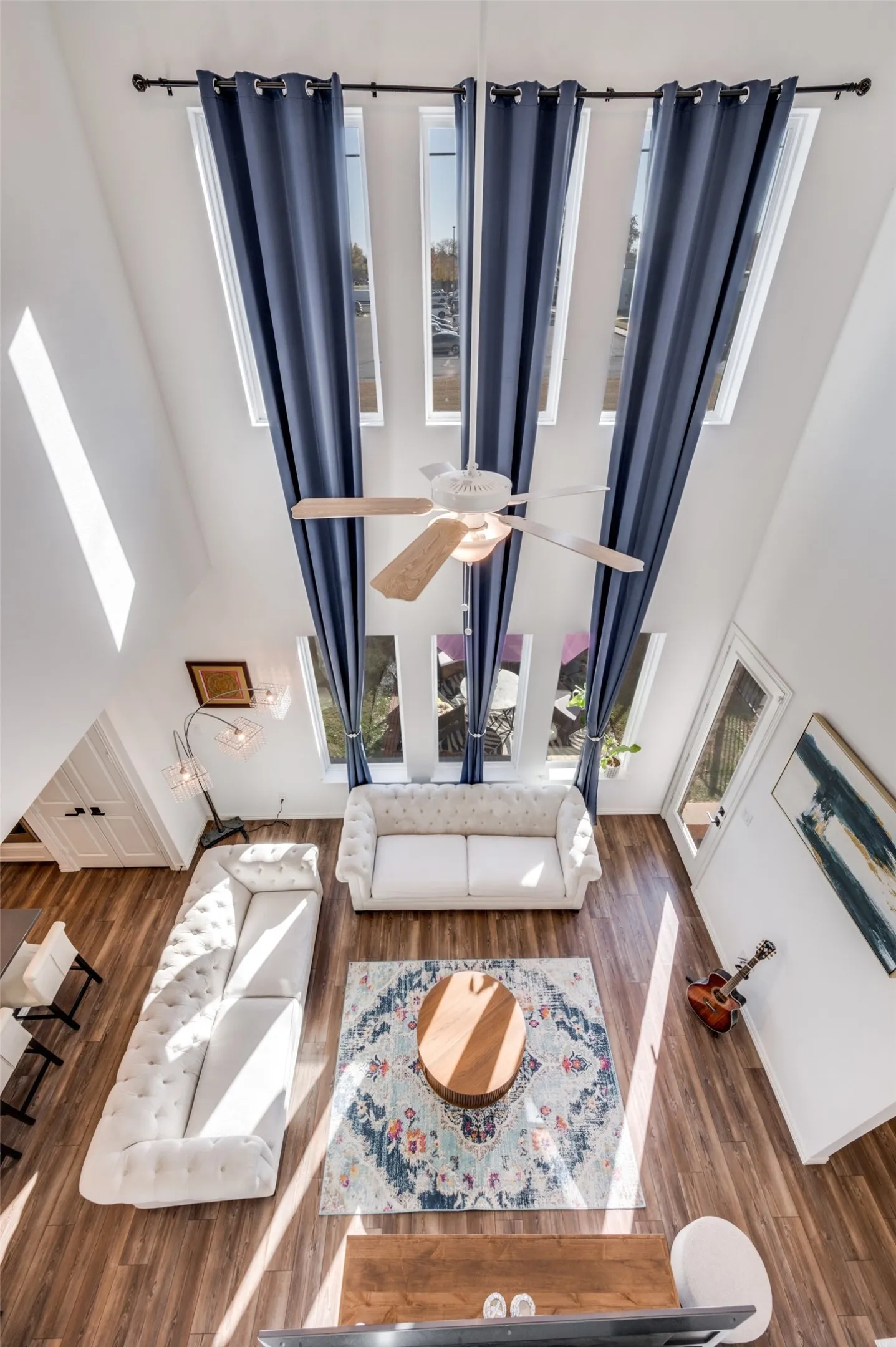 Vaulted ceiling with multiple windows, wood-finish flooring, and a ceiling fan