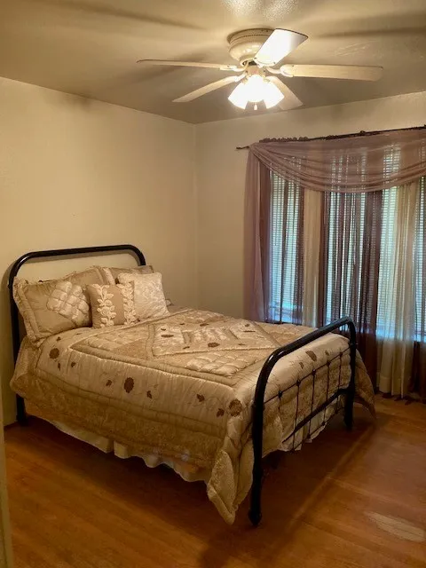 Recessed bay window, wood-finish flooring, ceiling fan, and light-toned walls