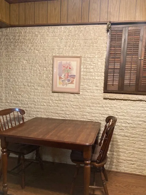 Brick accent wall with wood-paneled ceiling trim and wood flooring