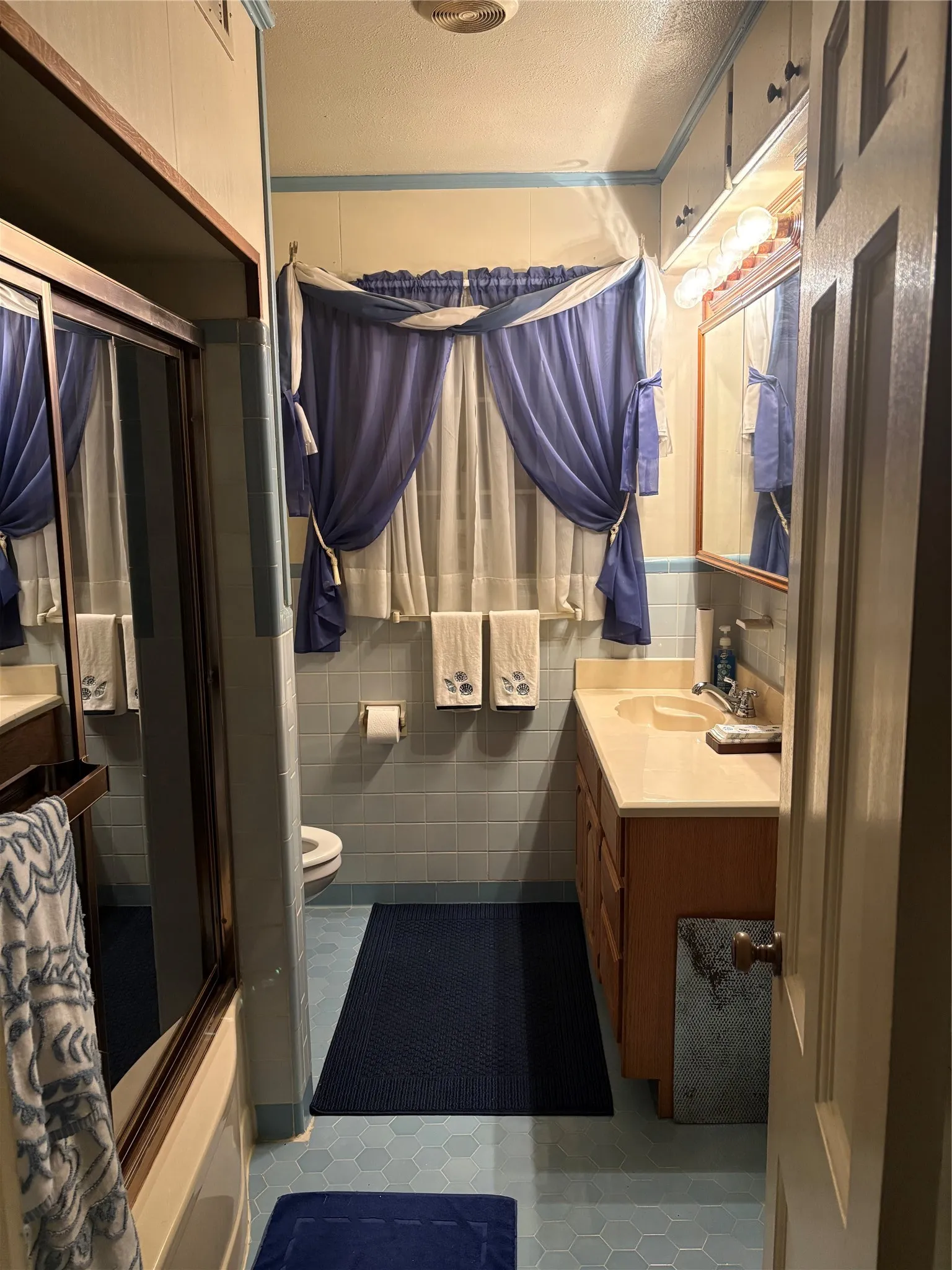Bathroom featuring hexagon tile flooring, a built-in vanity with a countertop sink, and a mirrored cabinet
