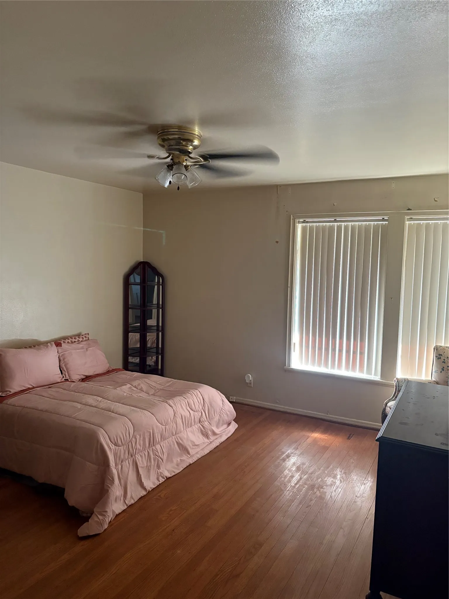 Hardwood flooring, ceiling fan with integrated lighting, multiple windows with blinds, neutral wall tones