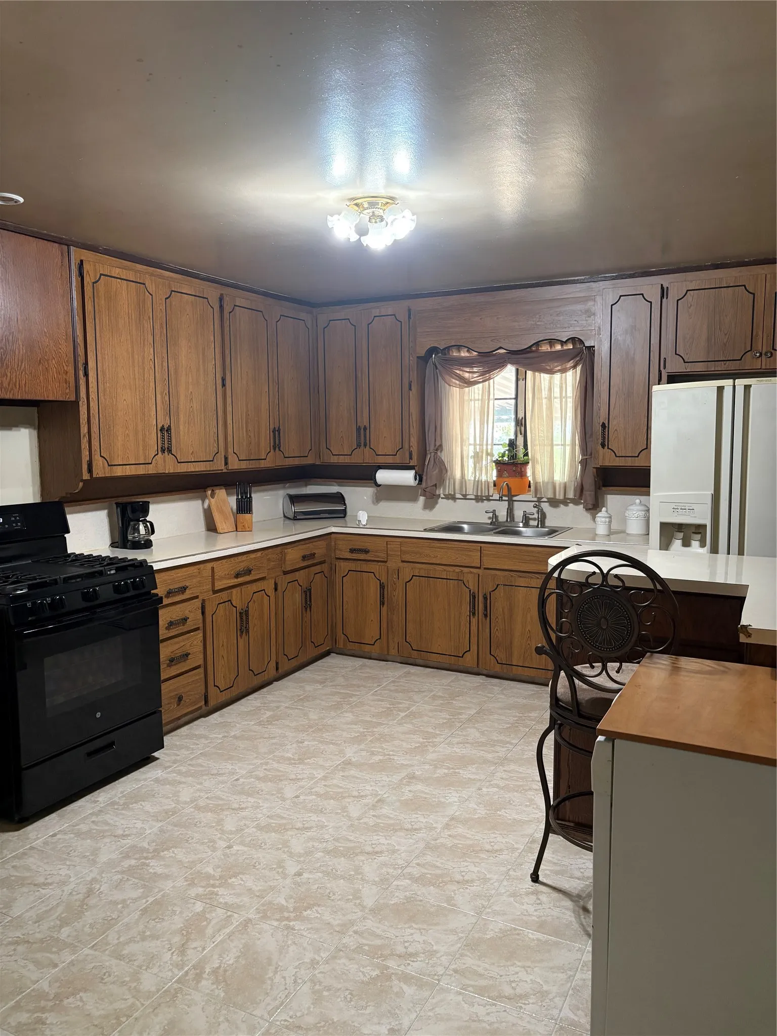 U-shaped kitchen featuring wood cabinetry, solid surface countertops, and tile flooring