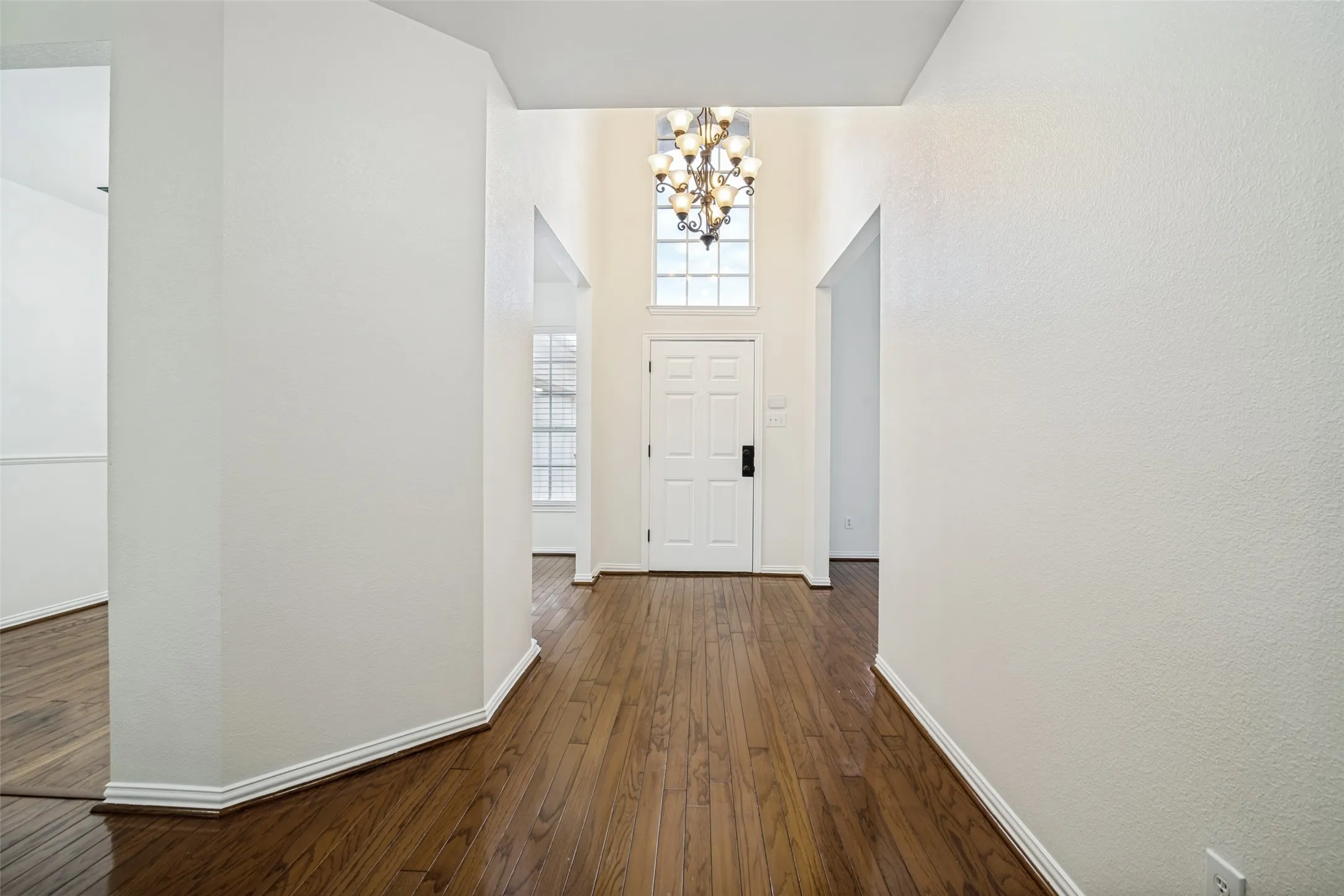 Two-story foyer with hardwood flooring, a multi-pane front door, and an upper transom window. Front living area and dining area are right here.