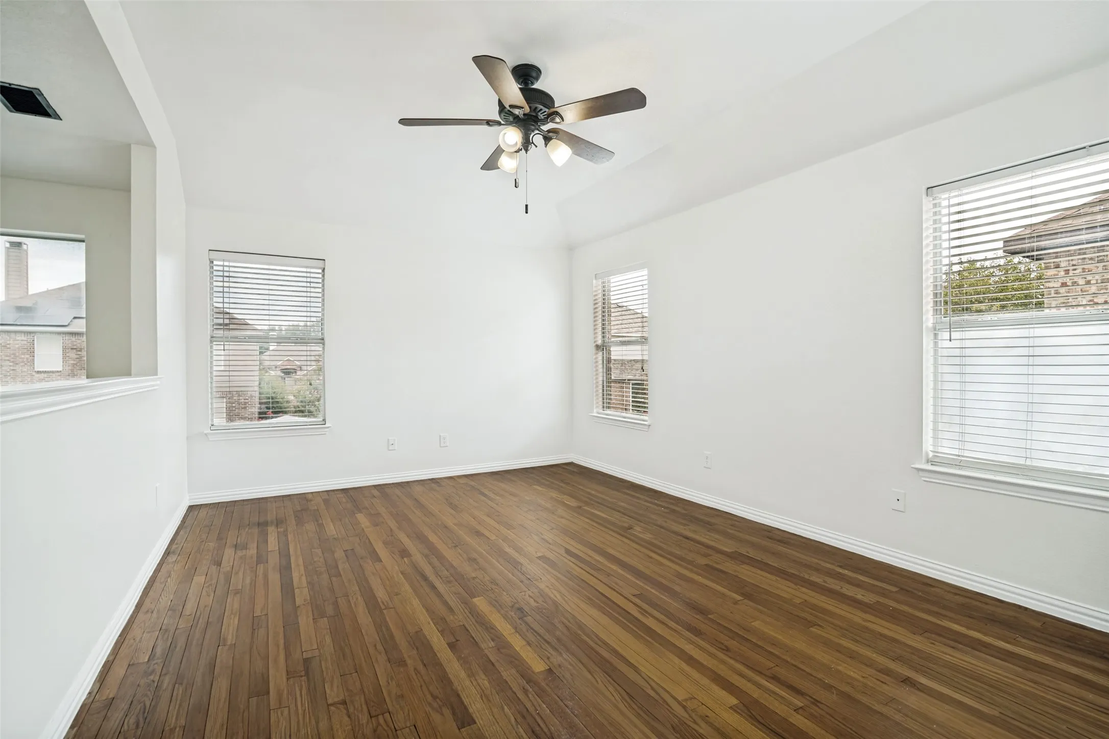 Vaulted ceiling with a four-light ceiling fan, wood-finish flooring, and white window blinds