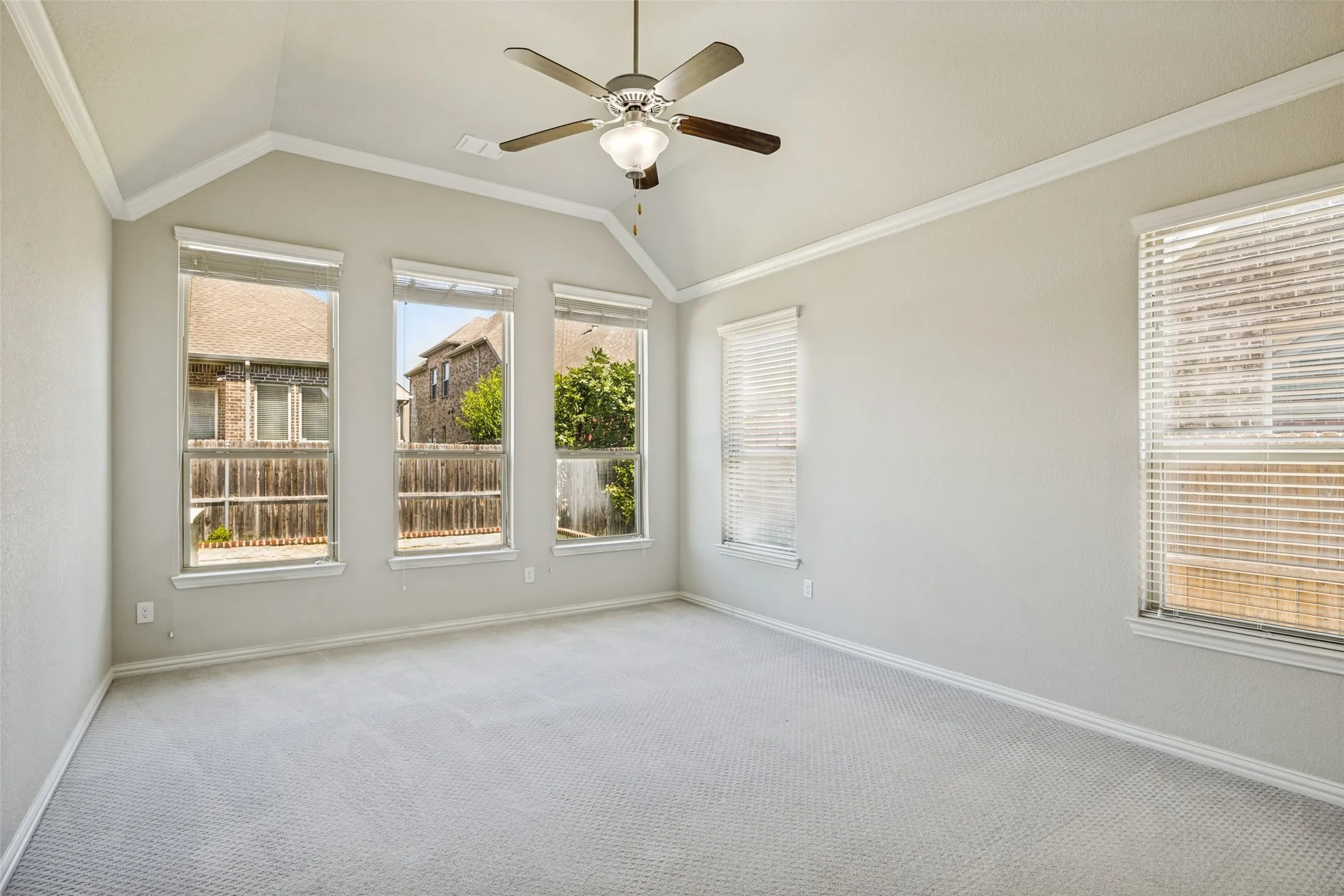 Vaulted ceilings with crown molding, ceiling fan, and multiple windows with blinds