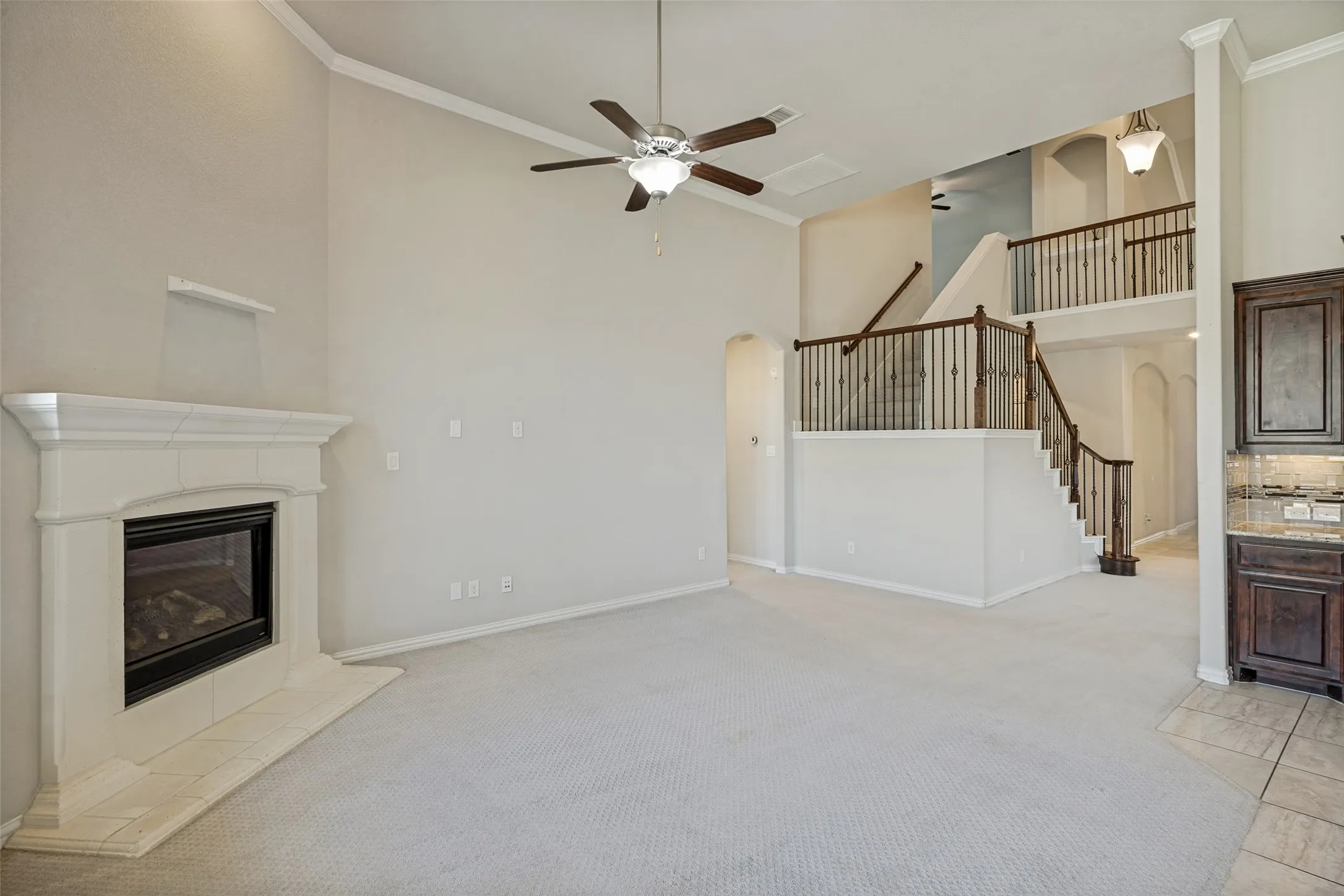 Great room with a corner fireplace, vaulted ceiling, and ceiling fan