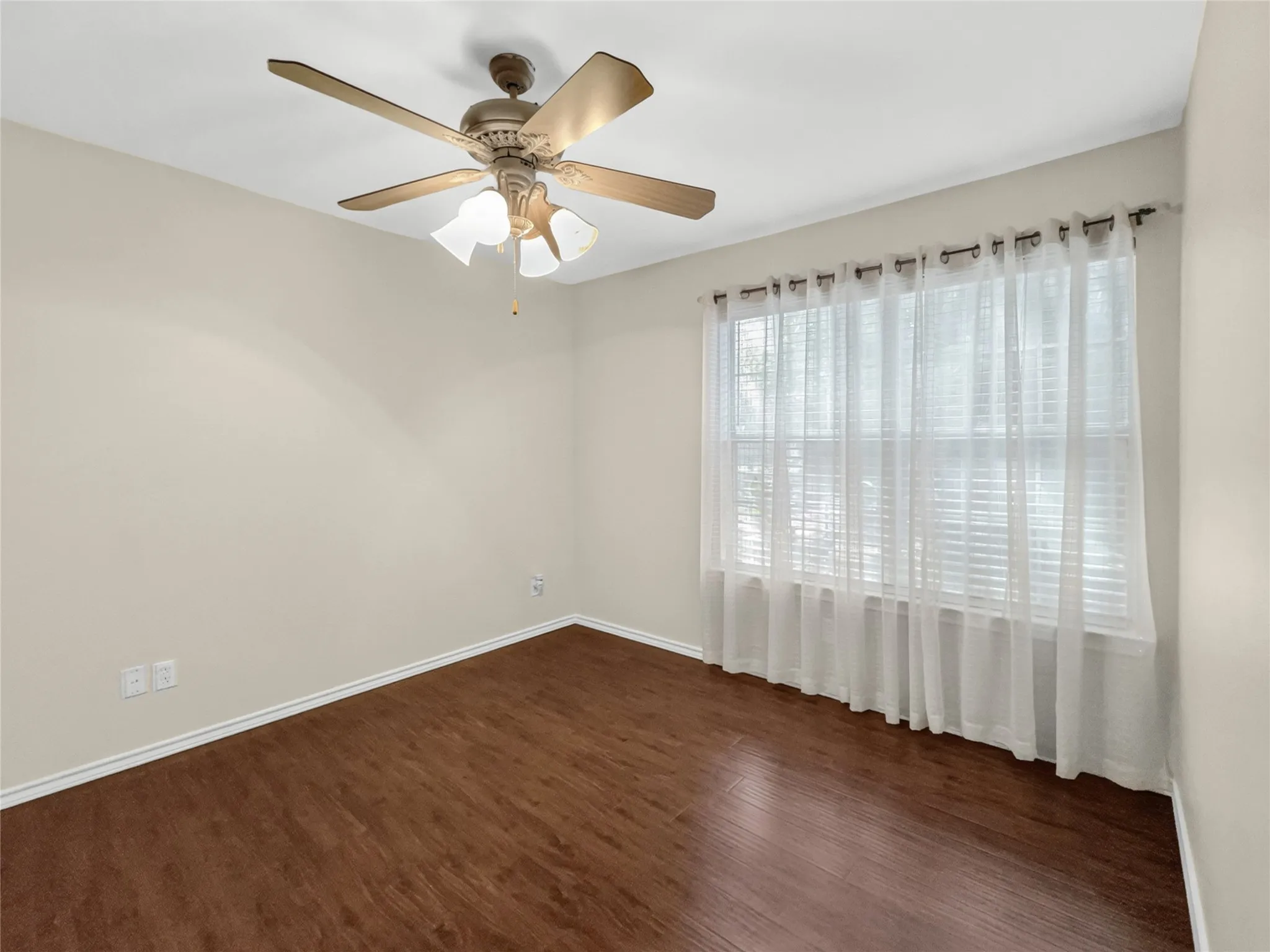 Wood-finish flooring with a ceiling fan light fixture and window with blinds