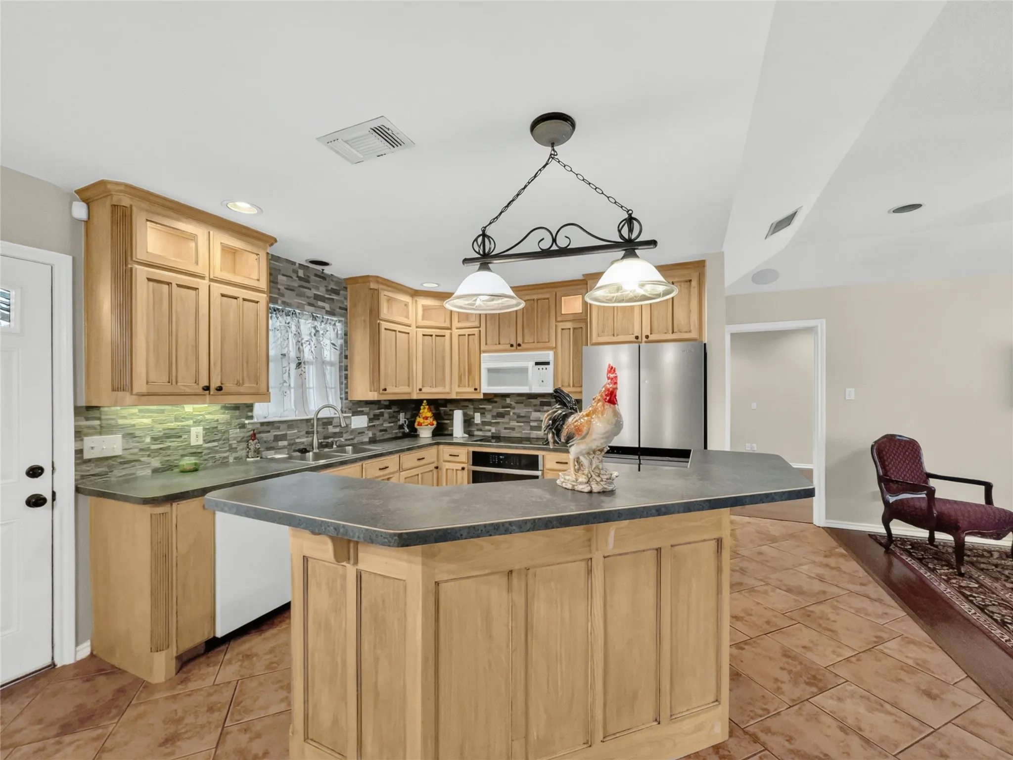 Wood-finish cabinetry with recessed lighting, tile backsplash, stainless steel appliances, a kitchen island, and tile flooring