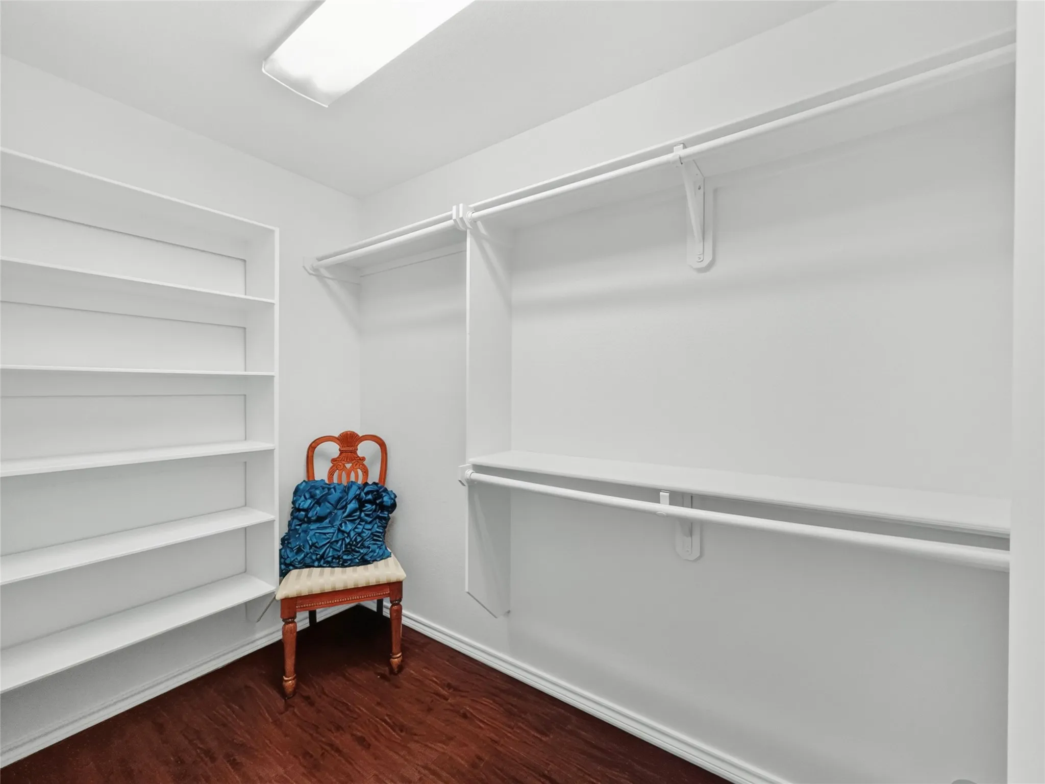 Recessed ceiling light, built-in shelving, white wall-mounted clothing rods, white wall-mounted shelving, and wood-finish flooring