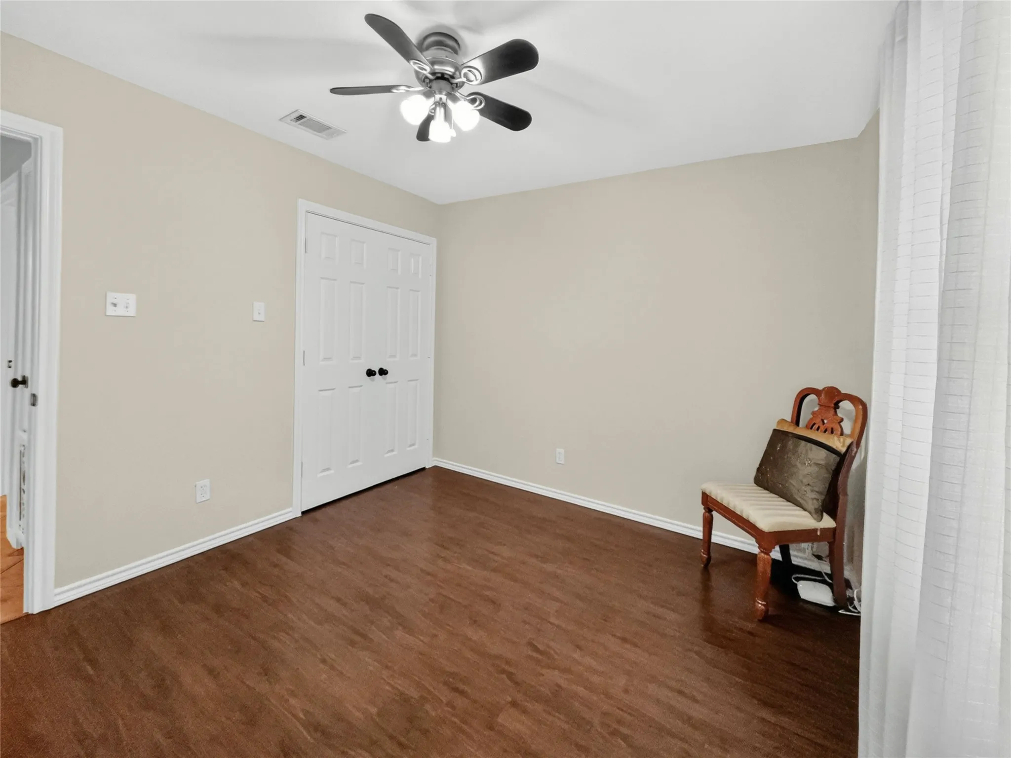 Wood-finish flooring, neutral wall tones, white trim, a ceiling fan with integrated lighting, and white bi-fold closet doors