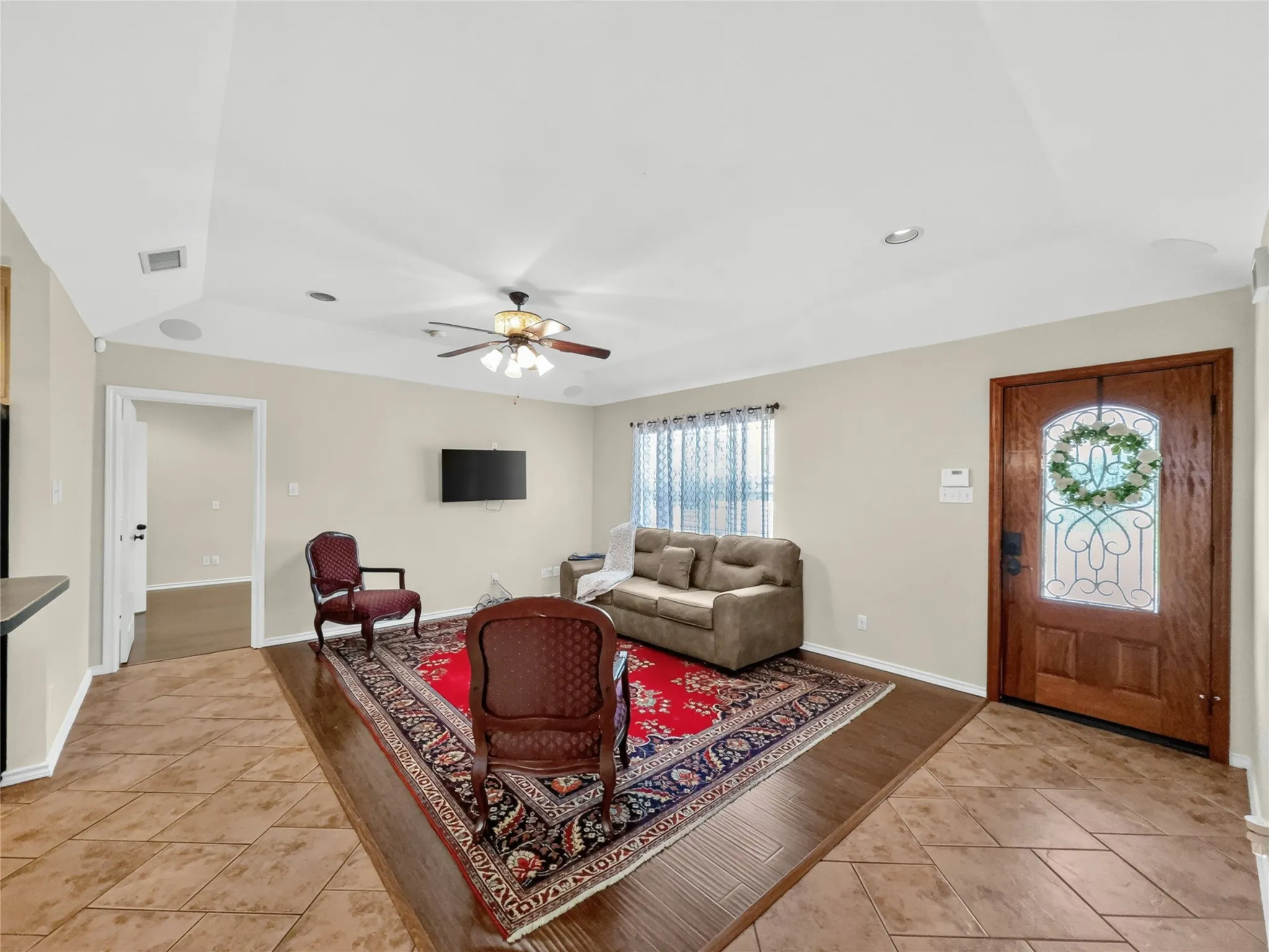 Entryway featuring a wood-panel door with decorative glass, tray ceiling, recessed lighting, ceiling fan, and mixed tile and wood-finish flooring