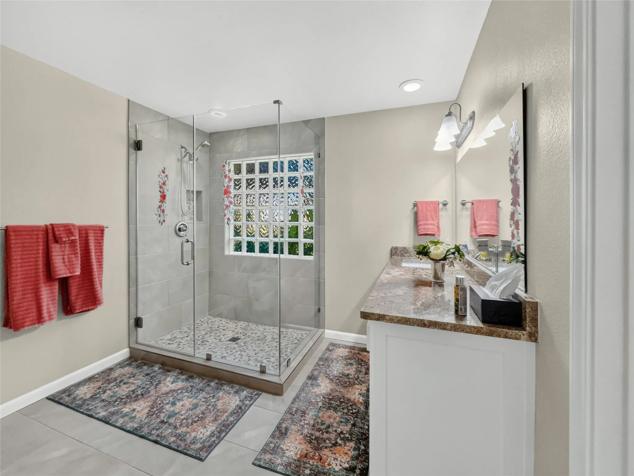 Glass-enclosed shower with pebble floor, tile surround, and built-in niche