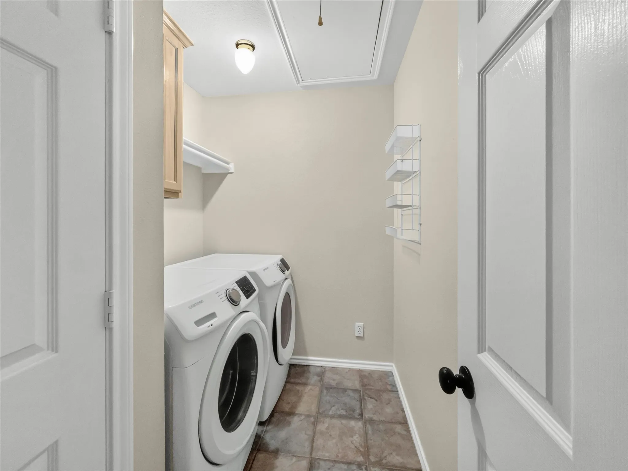 Utility area featuring tile flooring, built-in cabinetry, wall shelving, and a ceiling light fixture