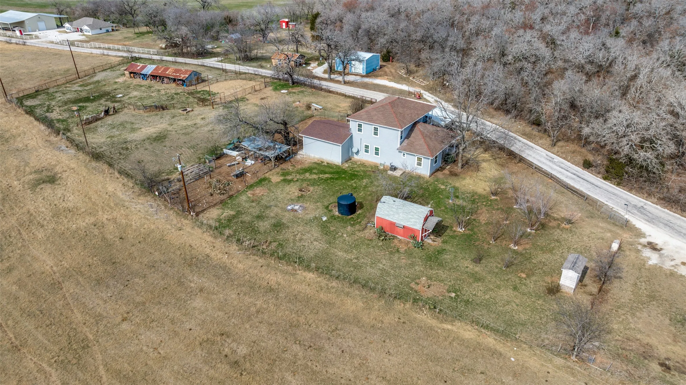 Expansive property featuring a two-story residence, multiple outbuildings, and a perimeter fence