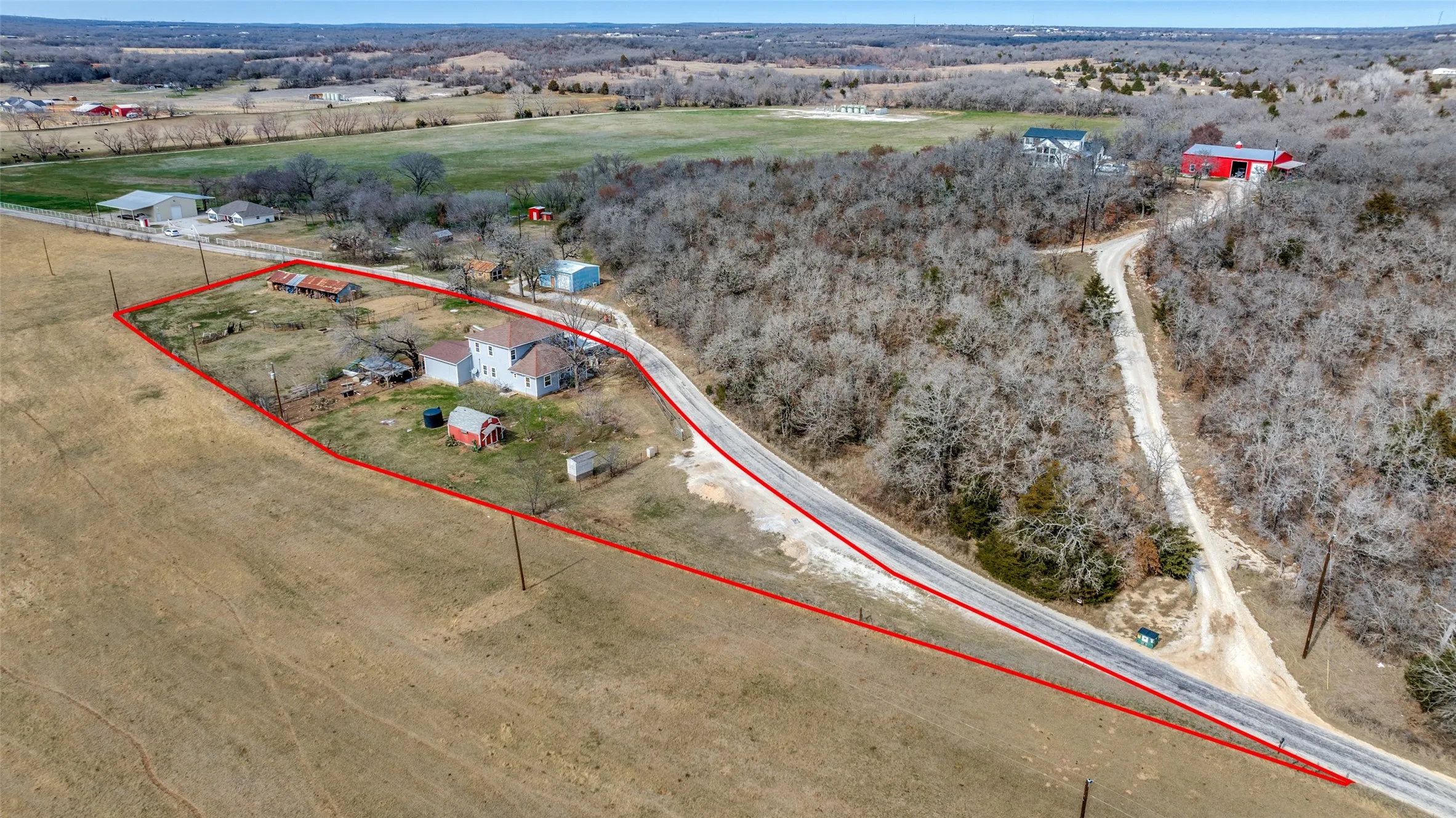 Expansive acreage with established residential structure, secondary structures, and direct road frontage