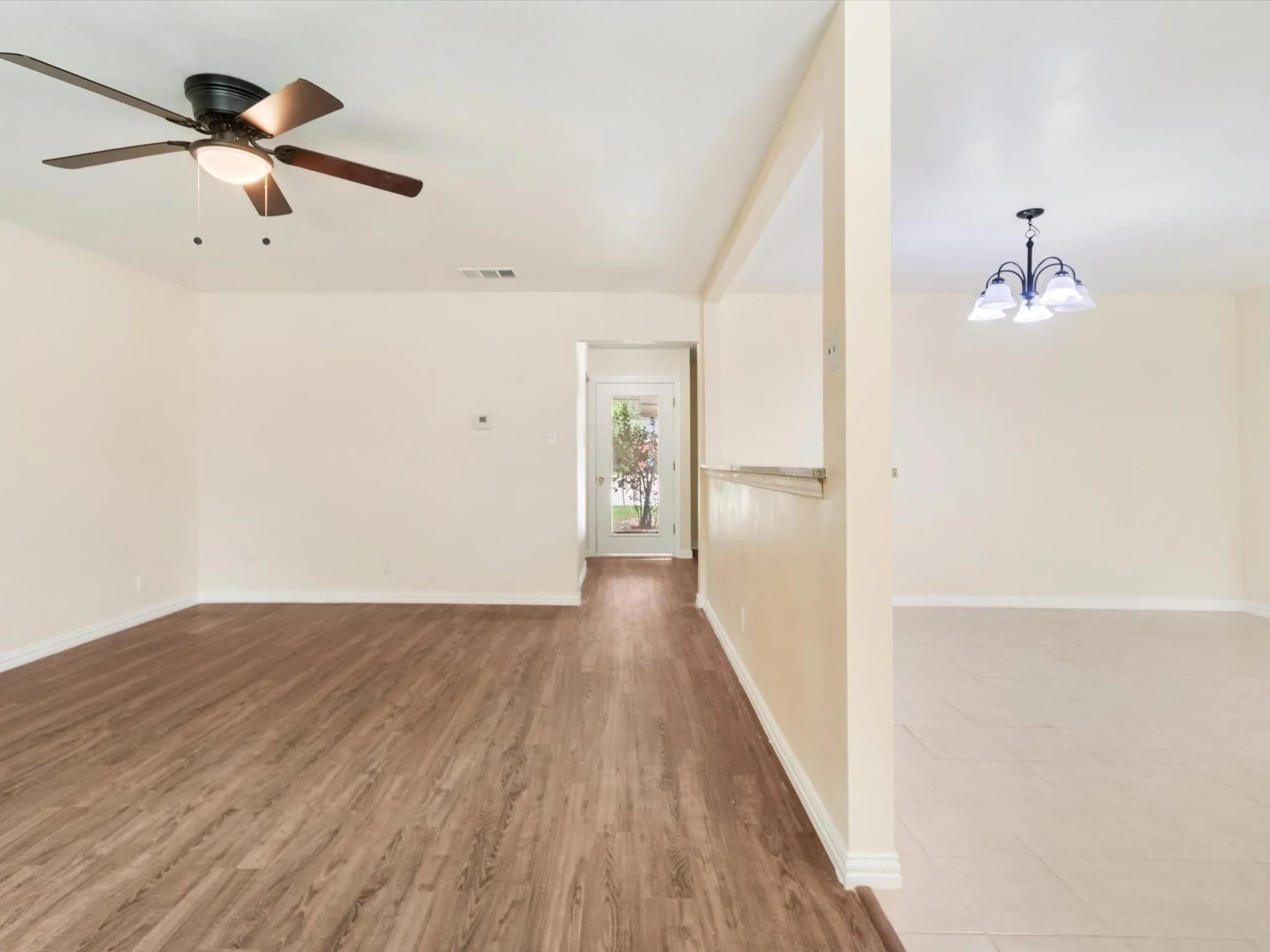 Wood-finish flooring, ceiling fan with integrated lighting, recessed wall opening, and tile flooring
