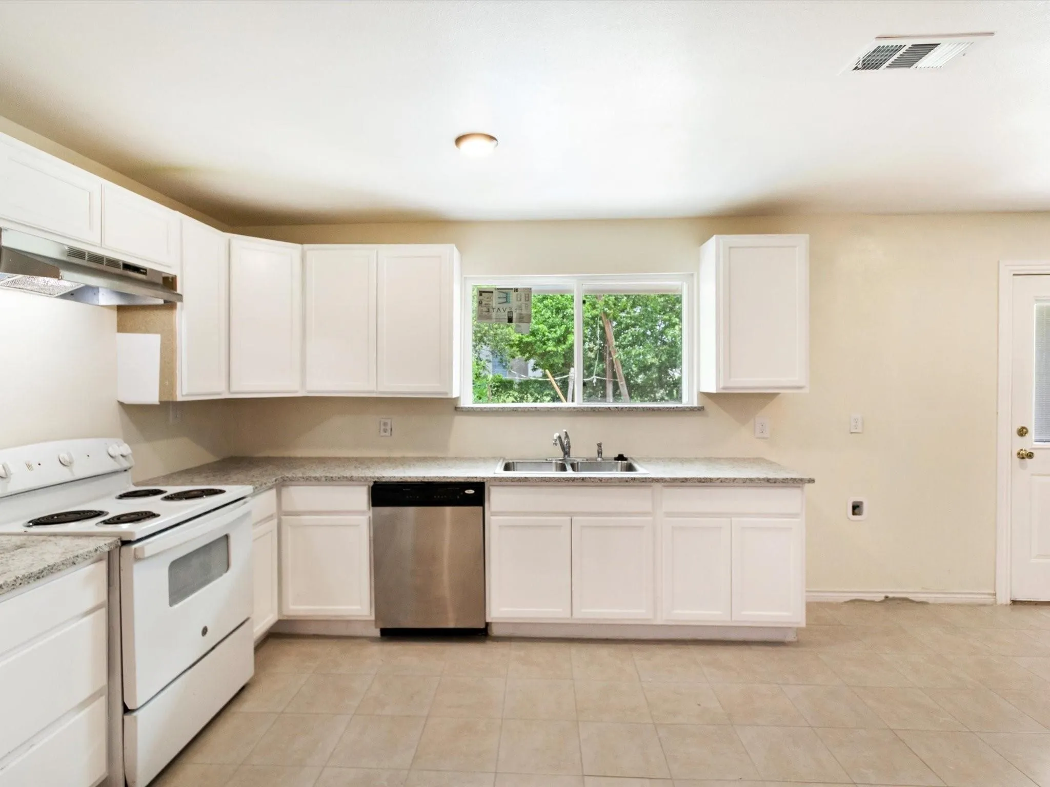 Kitchen featuring white cabinetry, light-toned countertops, a stainless steel dishwasher, a white range, and tiled flooring