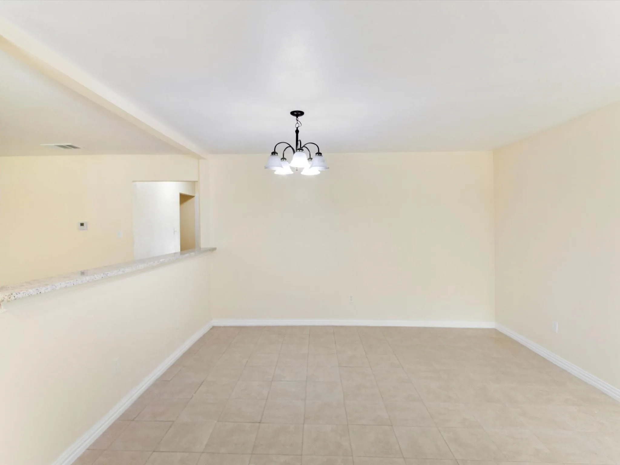 Overhead light fixture, tile flooring, half-wall with countertop surface, wall-mounted thermostat