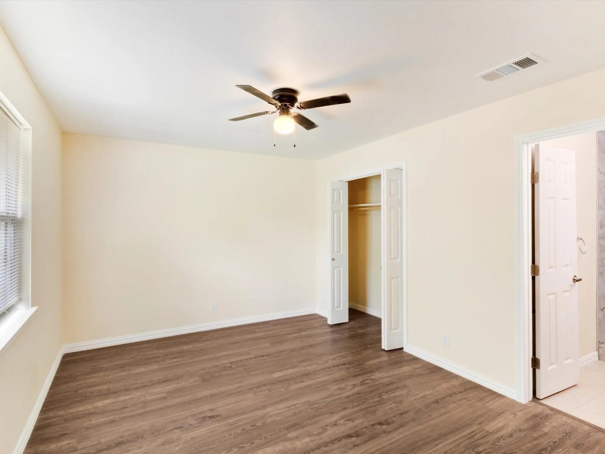 Wood-finish flooring, ceiling fan, and window with blinds