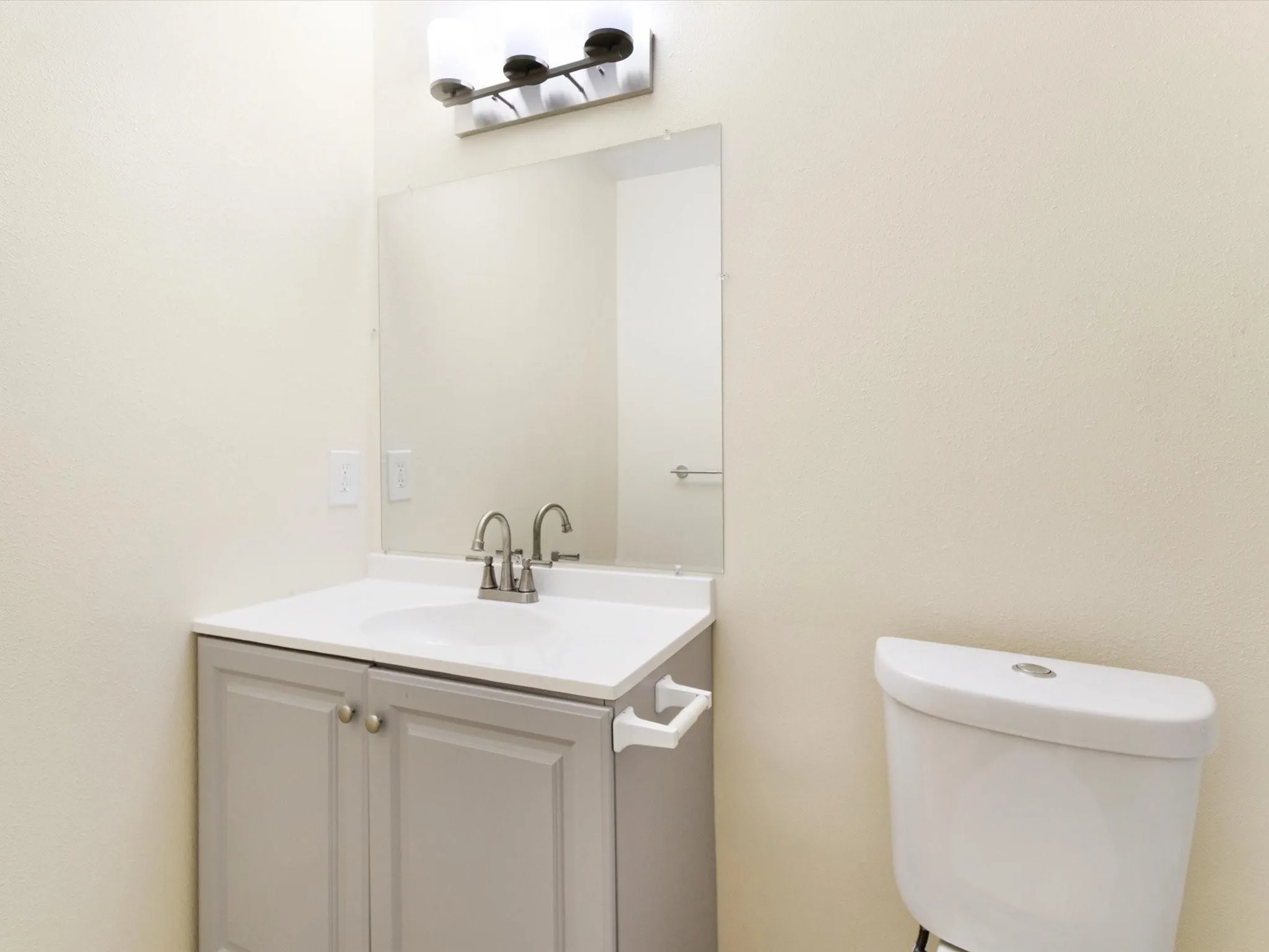 Vanity with integrated sink, dual-handle faucet, and surface-mounted mirror