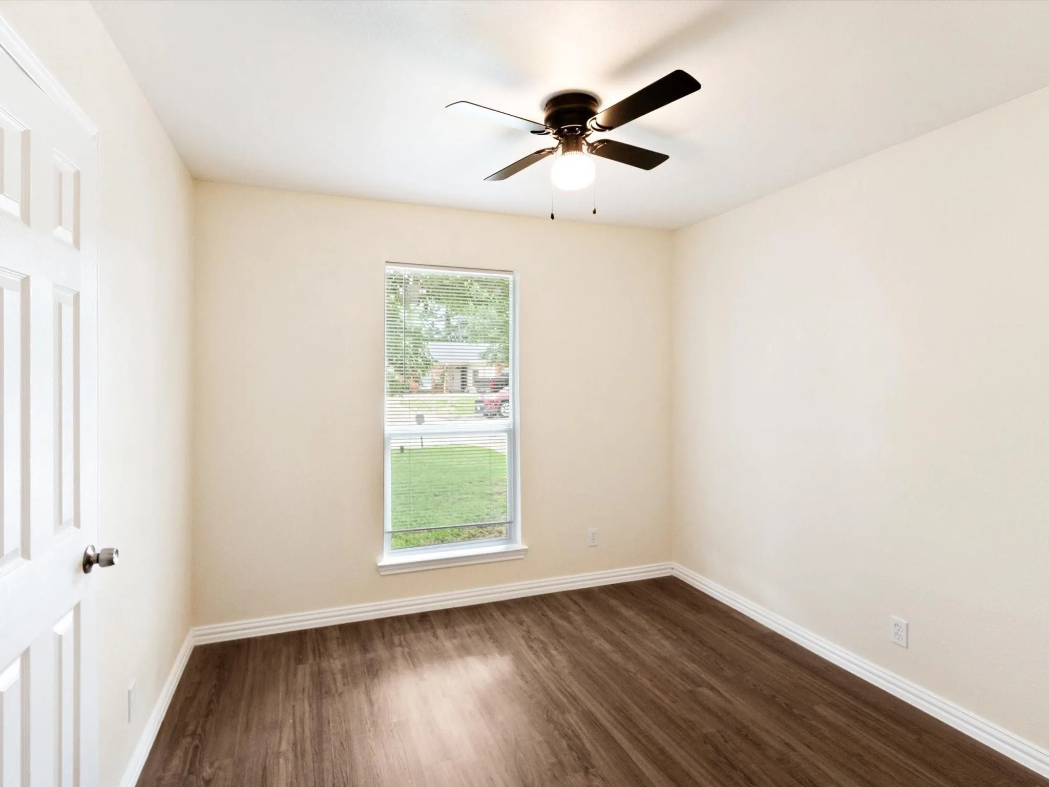 Wood-finish flooring, single window, overhead ceiling fan with light fixture, and paneled interior door
