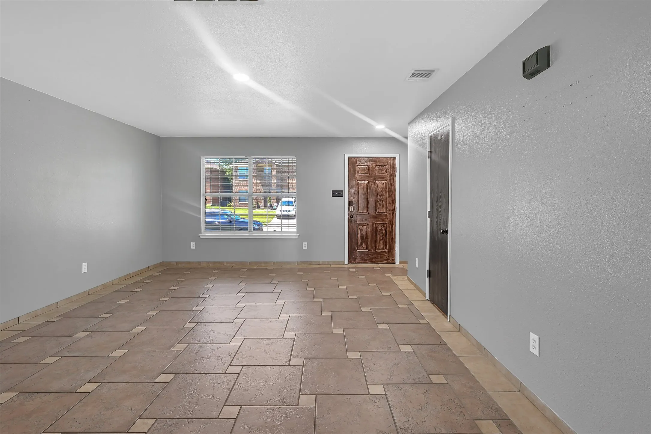 Spare room featuring a textured wall and light stone finish floors