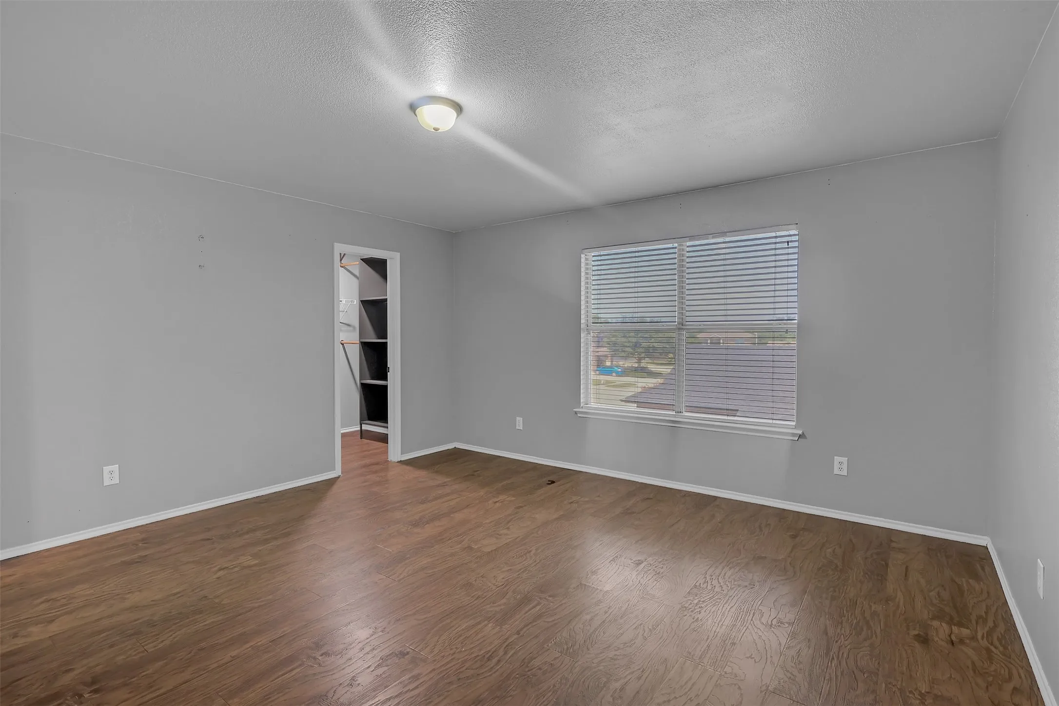 Empty room with a textured ceiling and dark wood finished floors