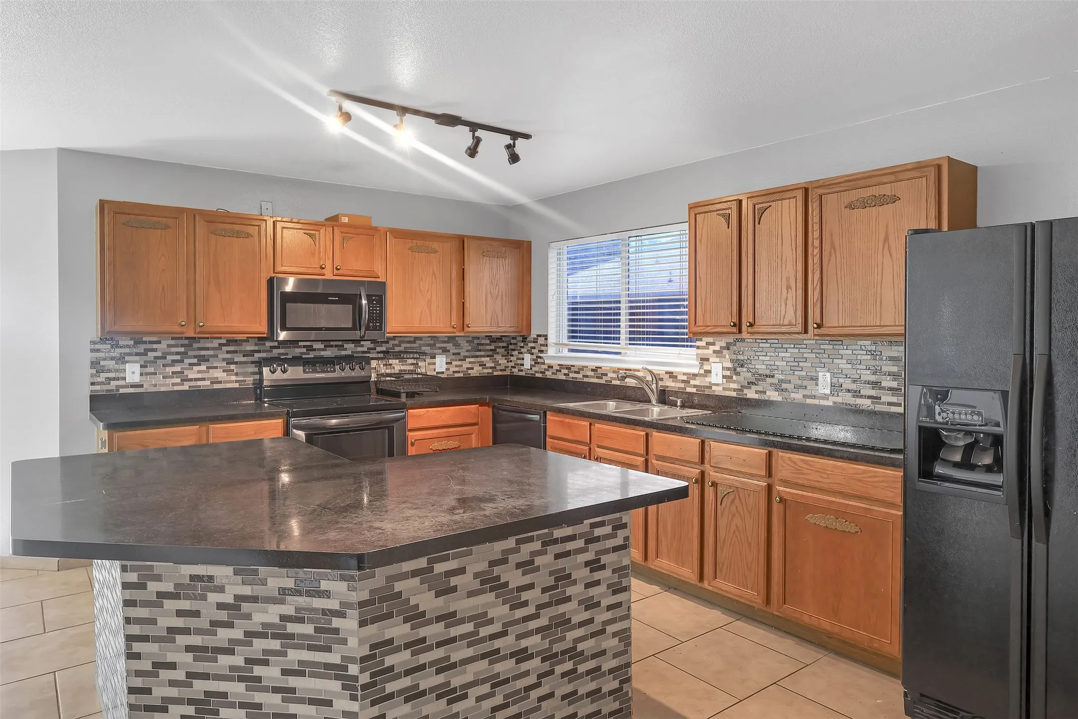 Kitchen featuring stainless steel appliances, tasteful backsplash, and brown cabinets