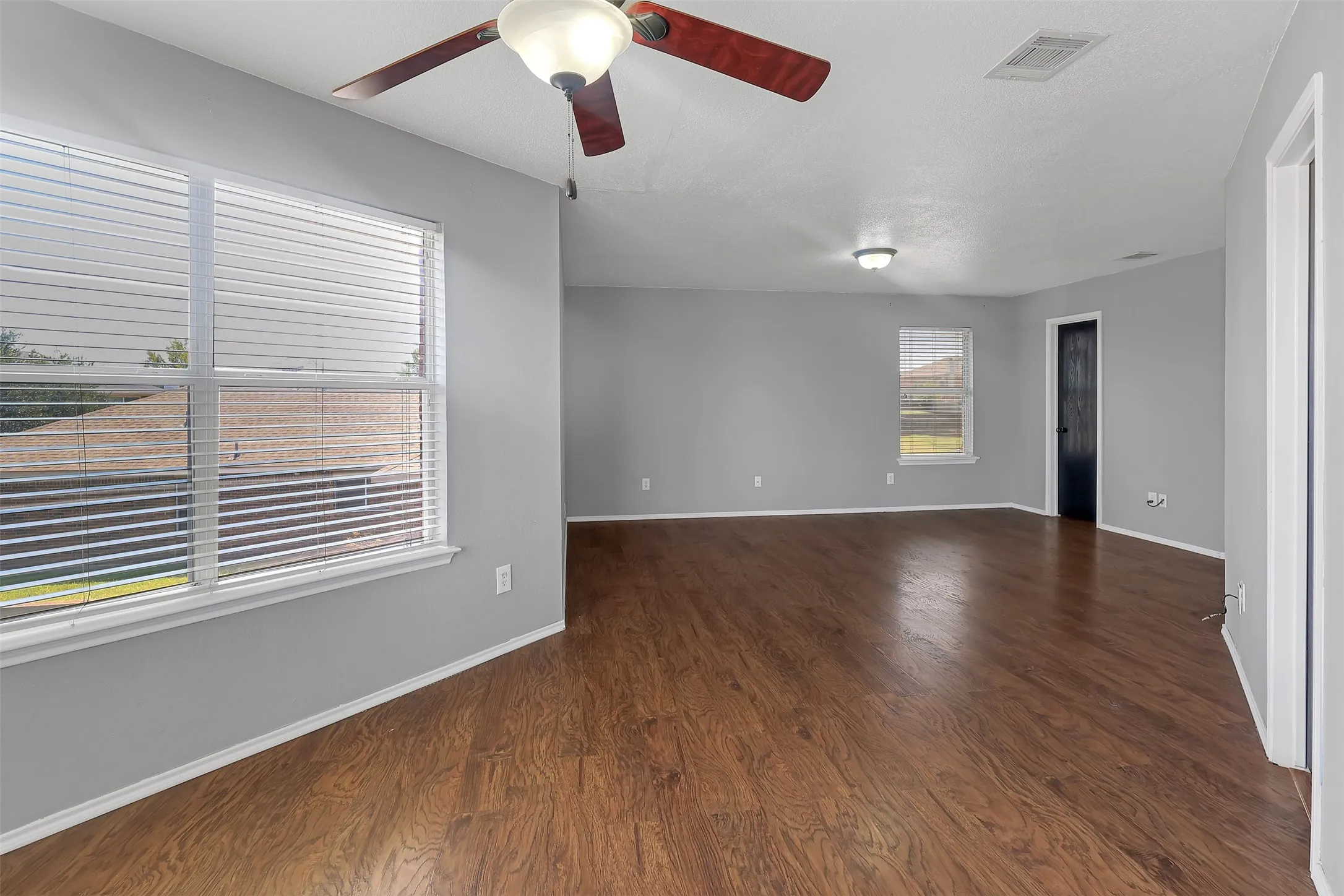Empty room with dark wood finished floors and ceiling fan