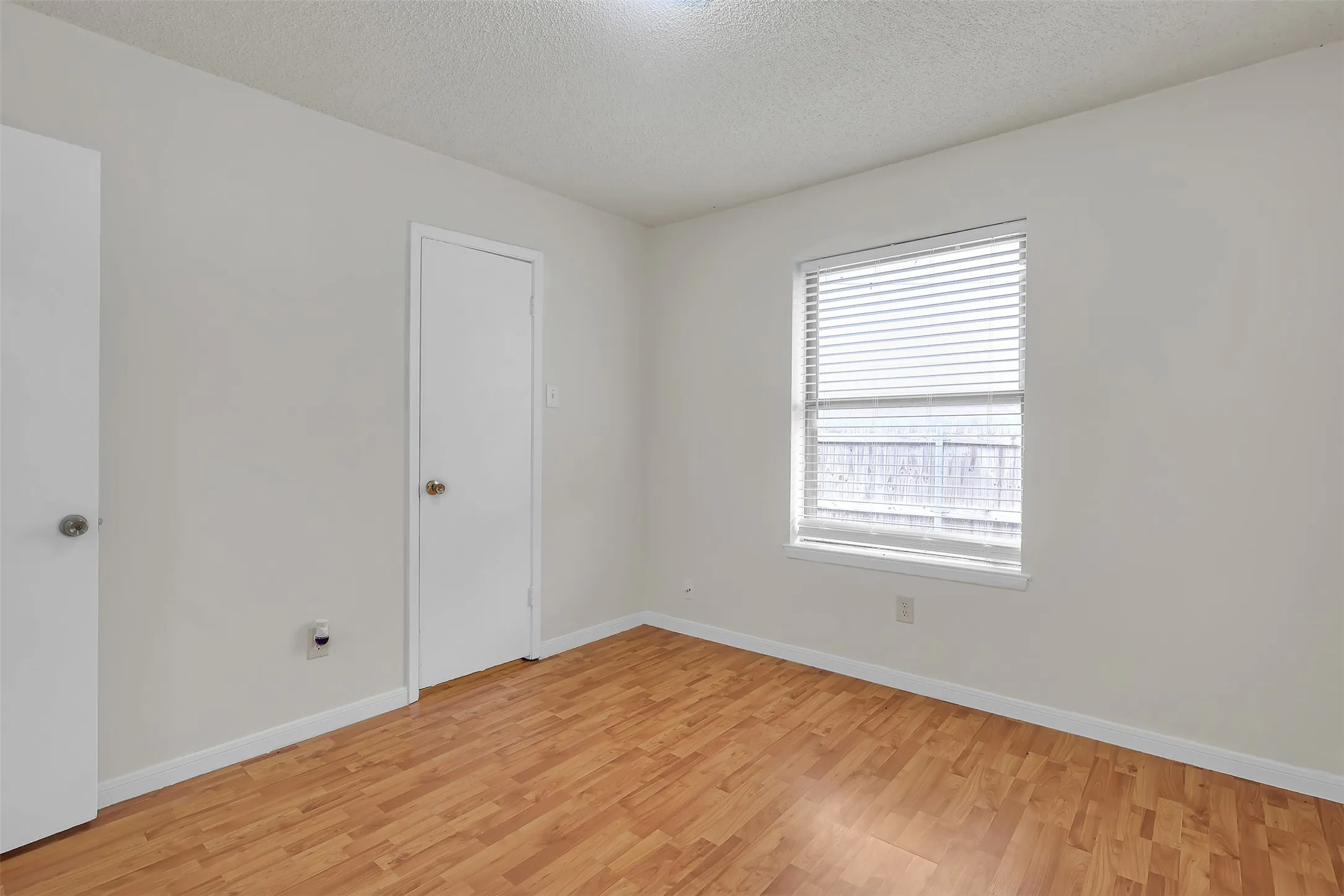 Spare room with light wood-type flooring and a textured ceiling