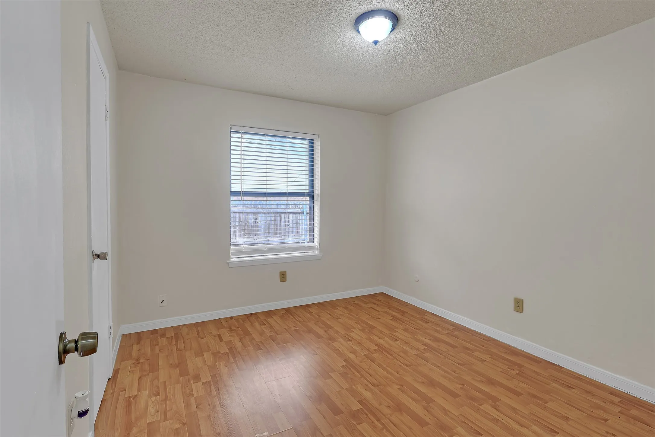 Empty room with light wood finished floors and a textured ceiling