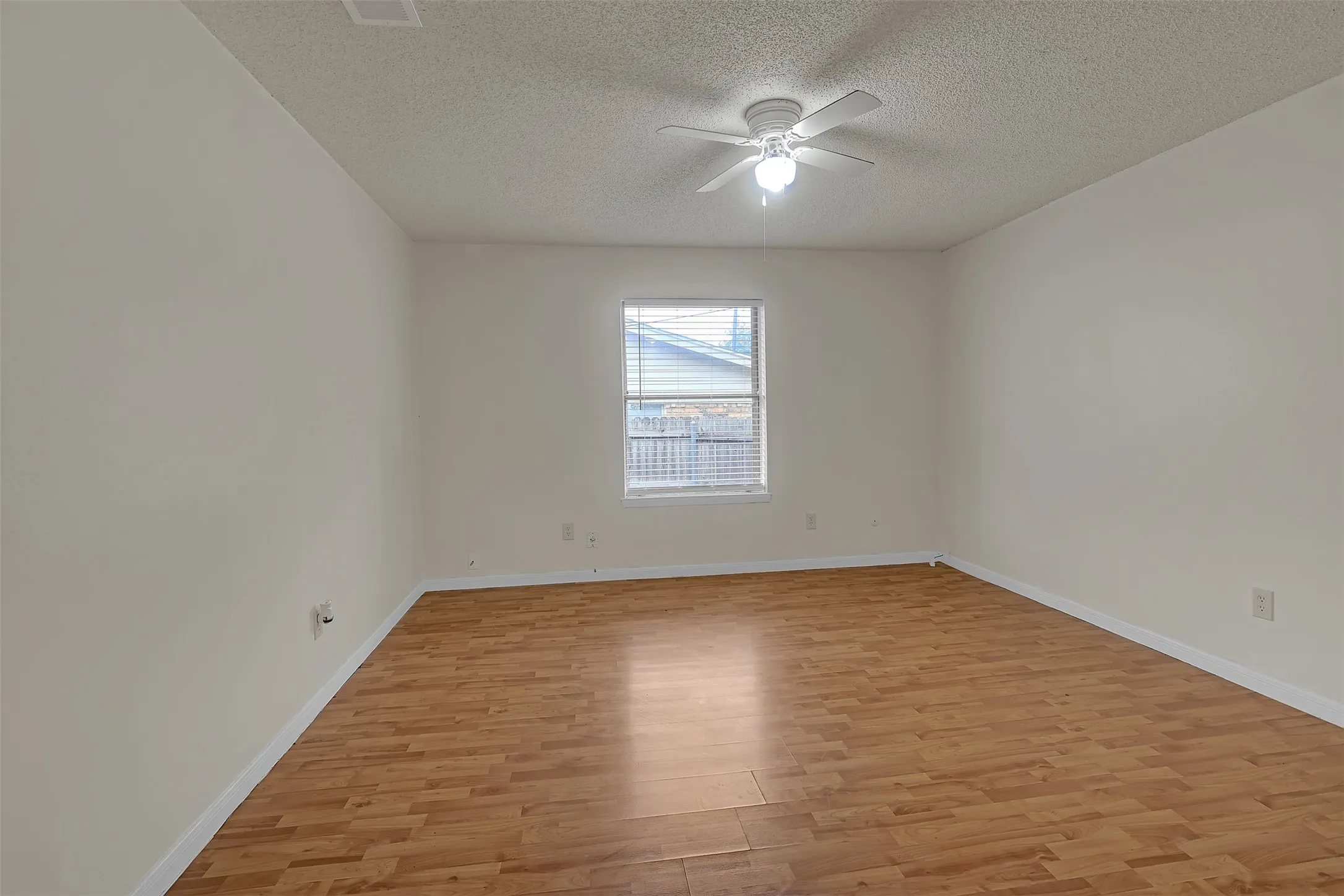 Unfurnished room featuring light wood-style floors, ceiling fan, and a textured ceiling