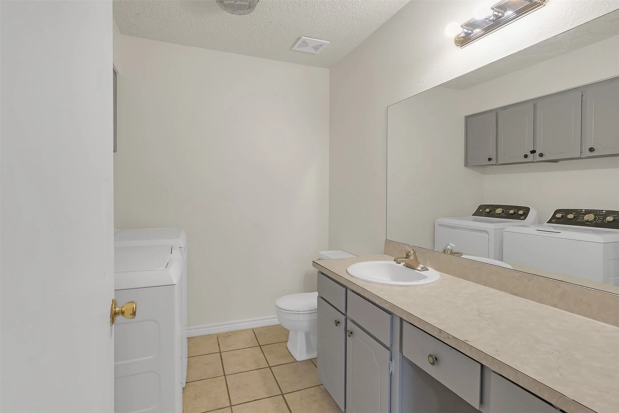 Bathroom featuring washer and clothes dryer, a textured ceiling, vanity, and tile patterned flooring