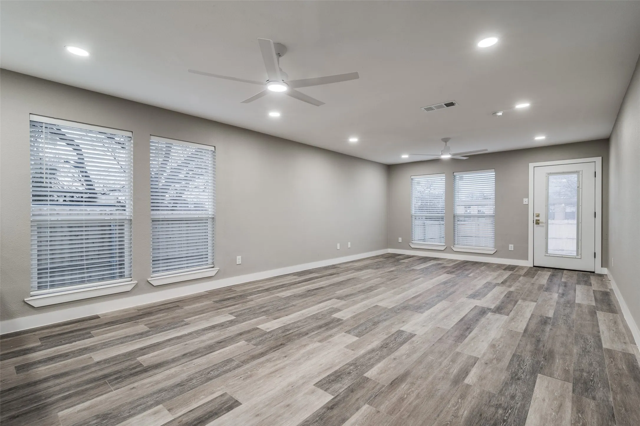 Kitchen featuring white shaker cabinetry, stainless steel appliances, a tile backsplash, light-toned countertops, and wood-finish flooring