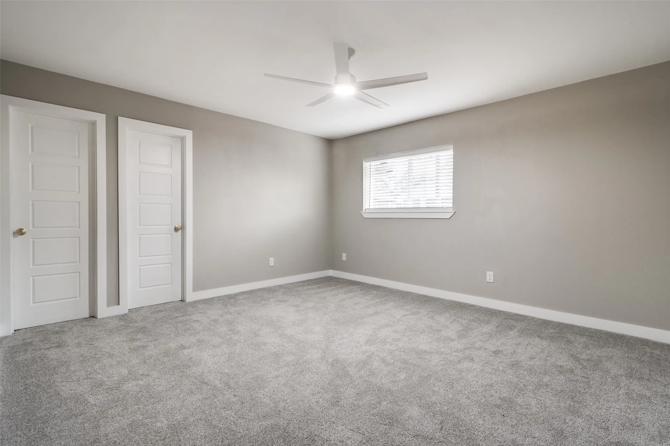 Neutral color palette, gray carpeting, dual pane window, ceiling fan with integrated lighting, and panel doors