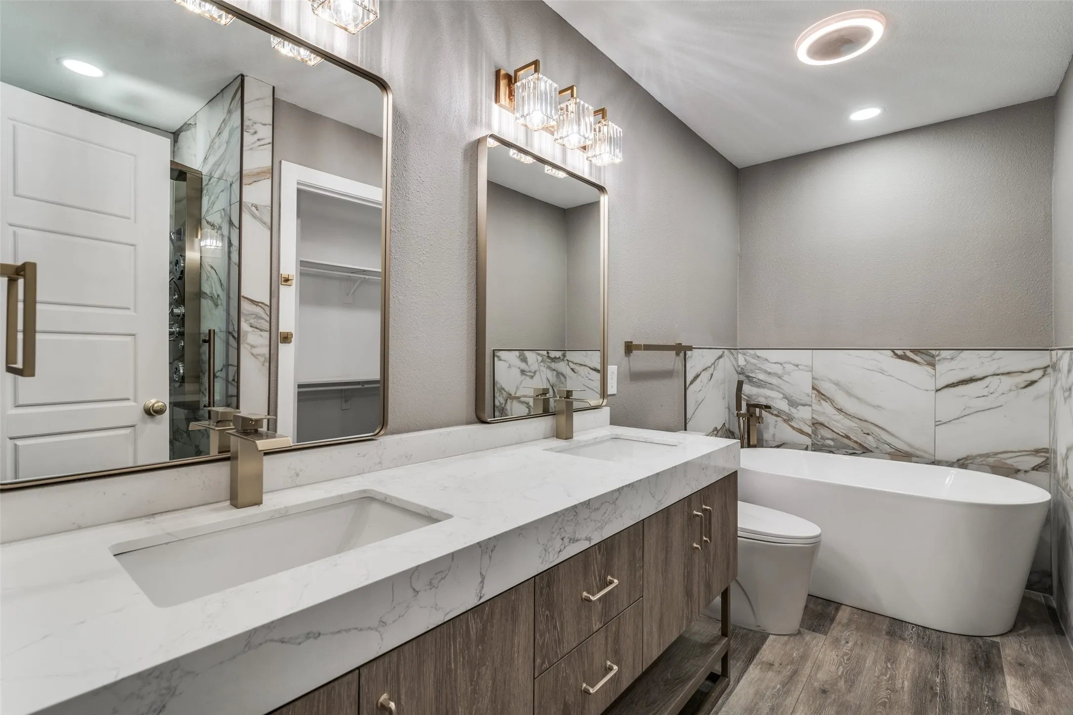 Dual vanity with undermount sinks, wood-finish cabinetry, and framed mirrors