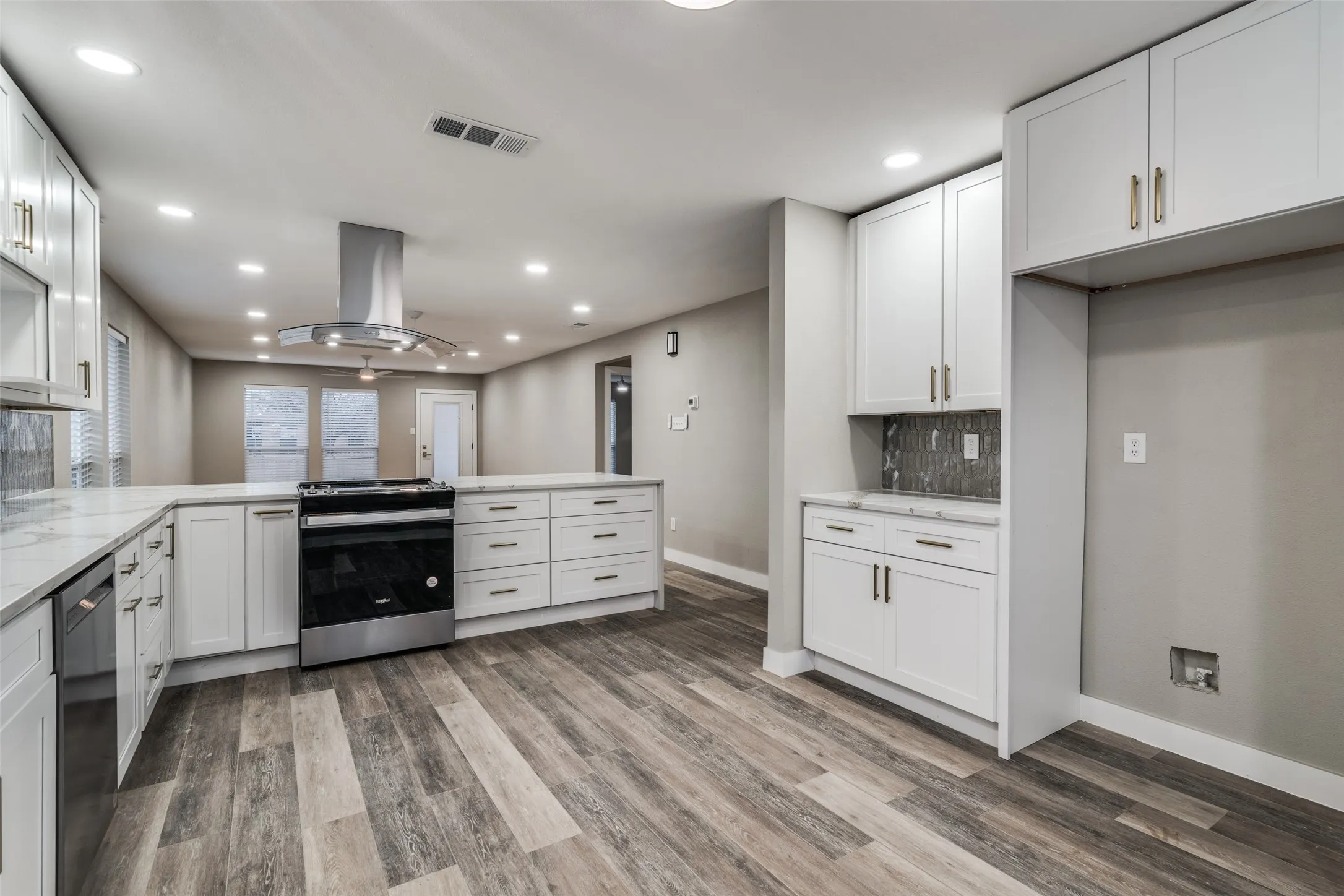 Modern kitchen featuring white cabinetry, light-toned countertops, stainless steel appliances, wood-finish flooring, and recessed lighting