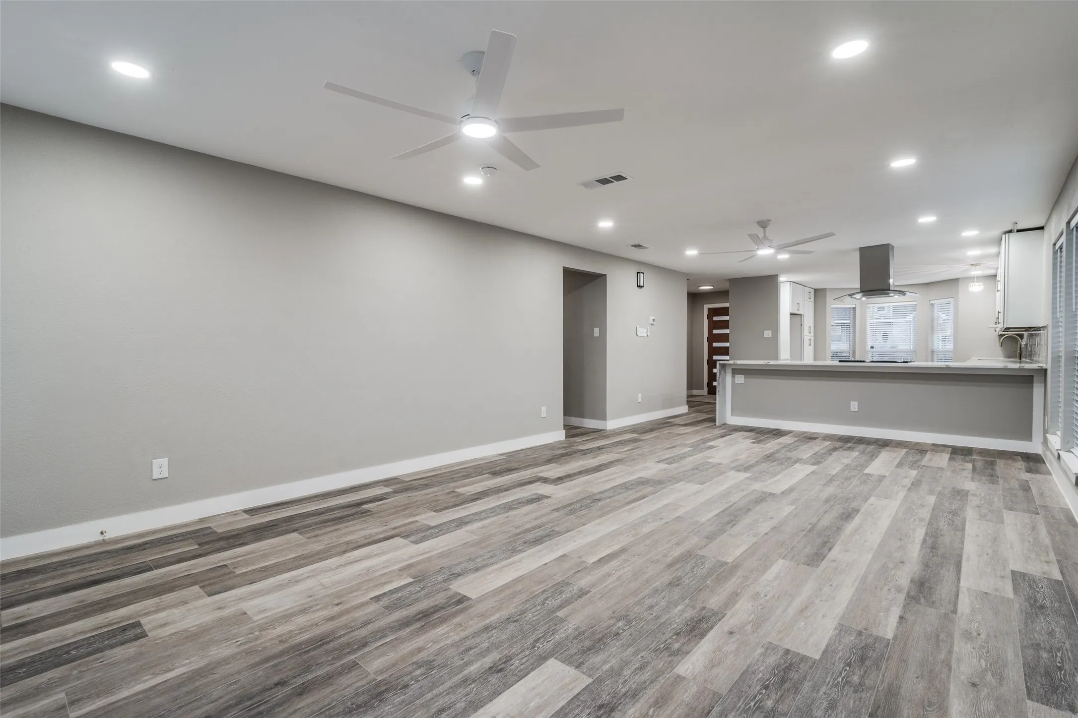 Open-concept living space featuring wood-finish flooring, recessed lighting, and ceiling fans