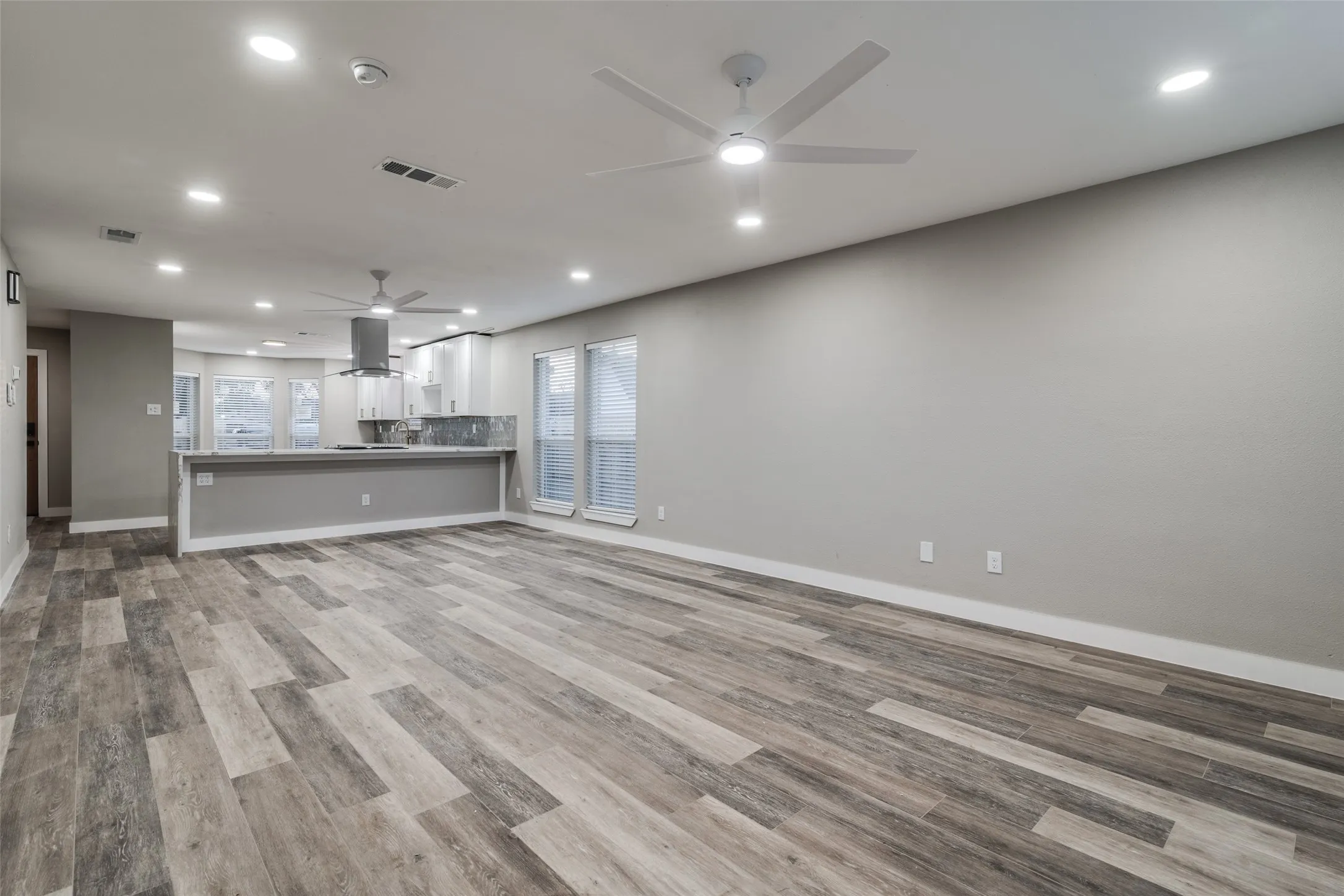 Open-concept living space featuring wood-finish flooring, recessed lighting, and ceiling fans