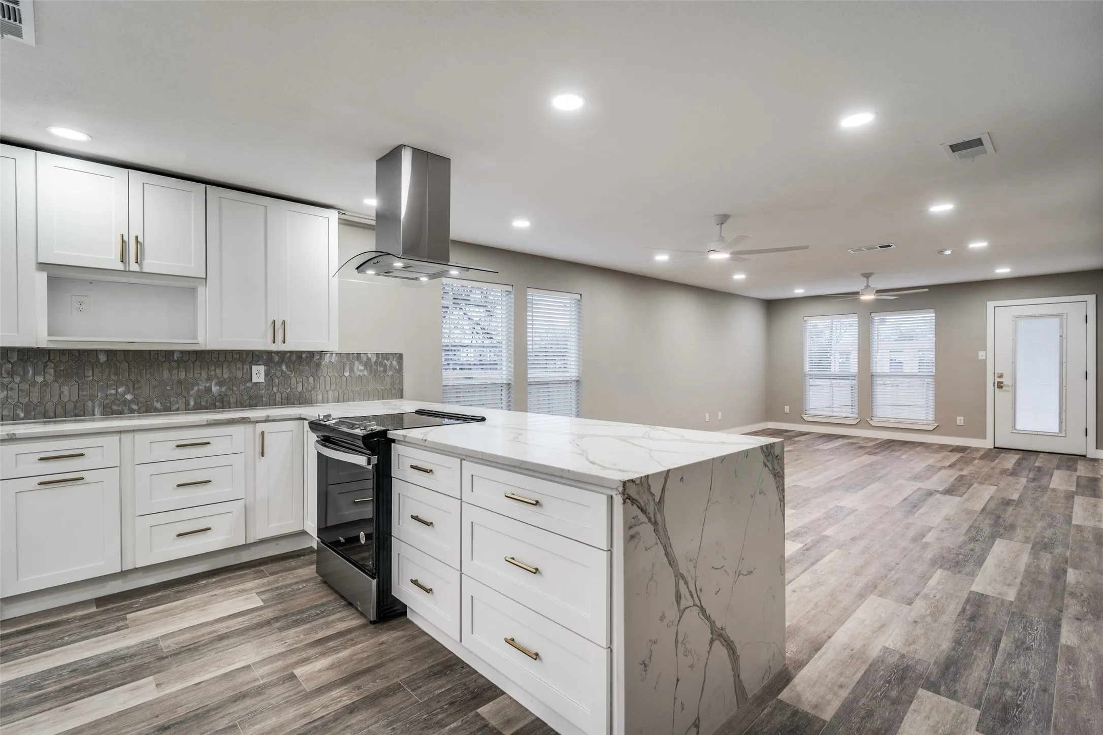 Open-concept living area featuring wood-finish flooring, recessed lighting, and ceiling fans