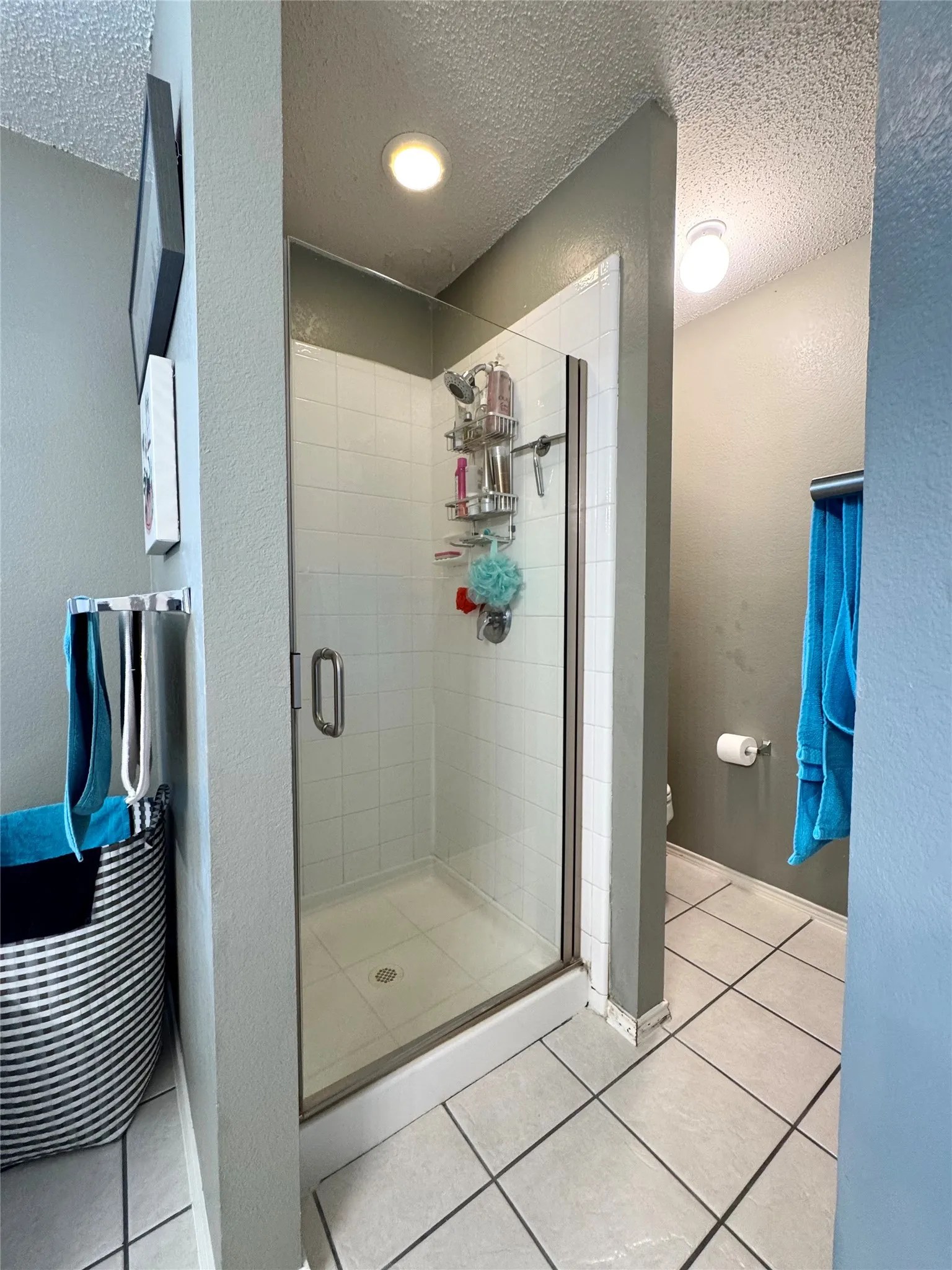 Glass-enclosed shower with white tiled walls and a white shower pan