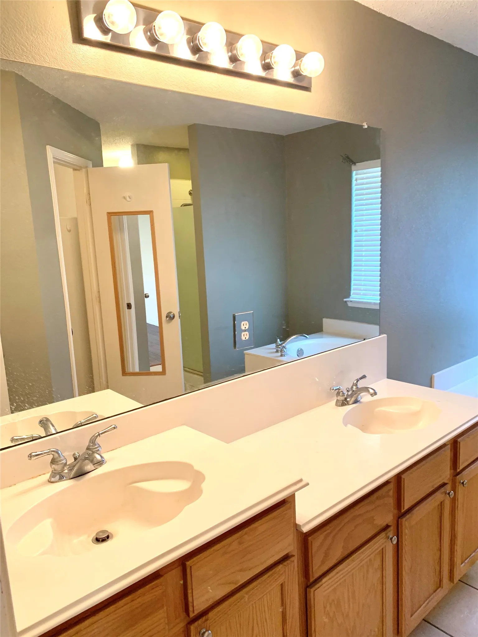 Dual vanity with white countertops, integrated sinks, and wood-finish cabinetry