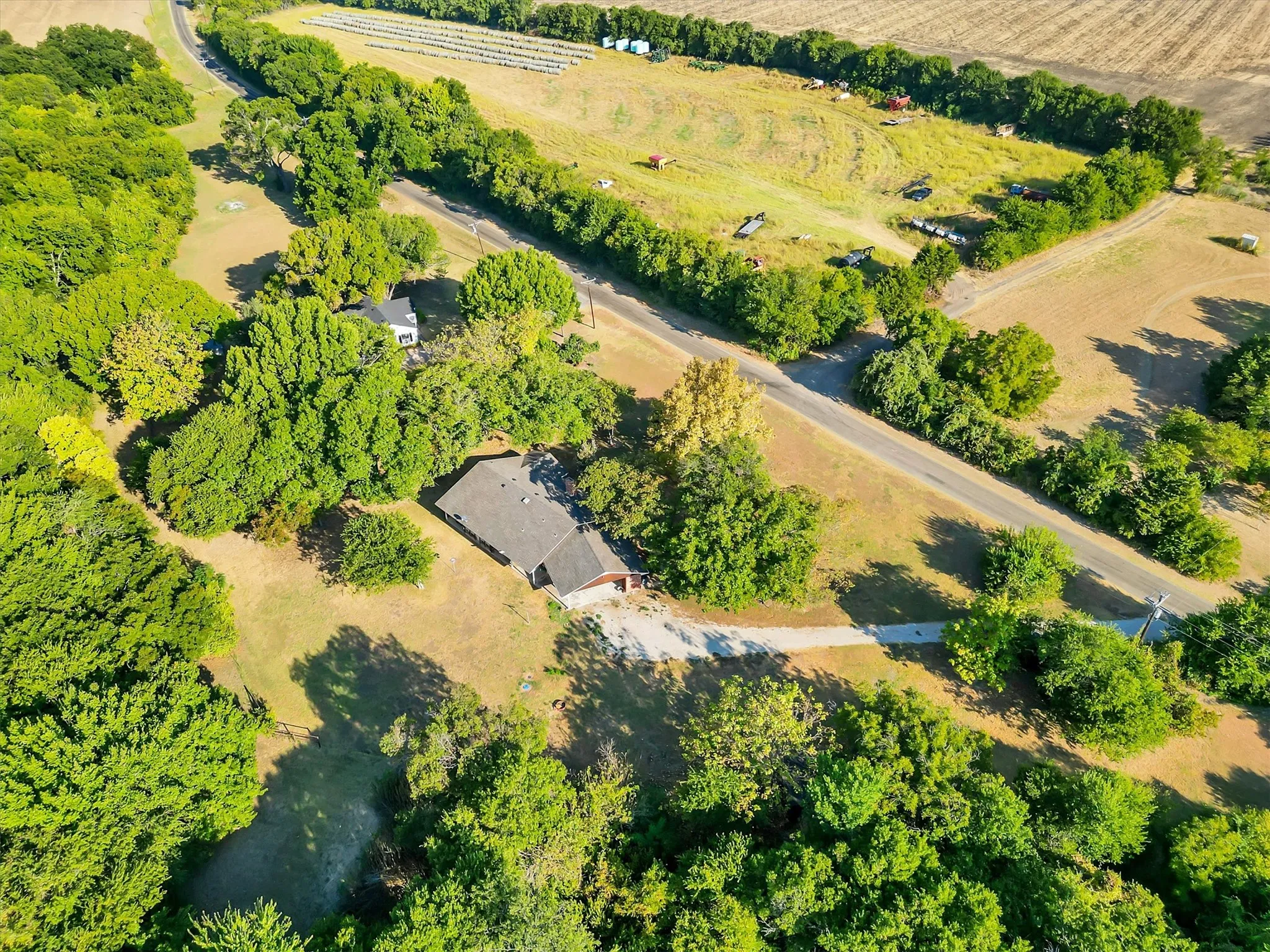 Property featuring a private driveway, mature trees, and a pitched roof