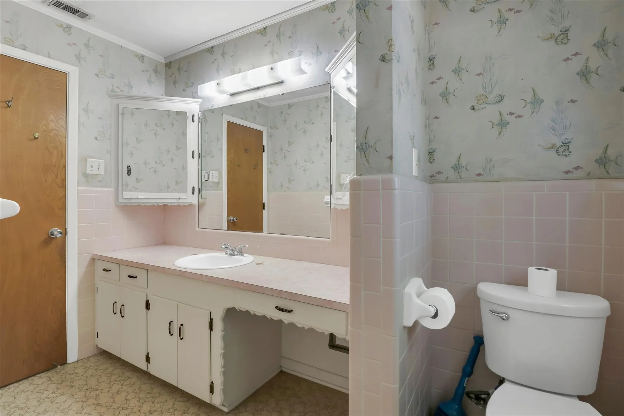 Bathroom featuring a vanity with a drop-in sink, wall-mounted mirror, medicine cabinet, and a toilet