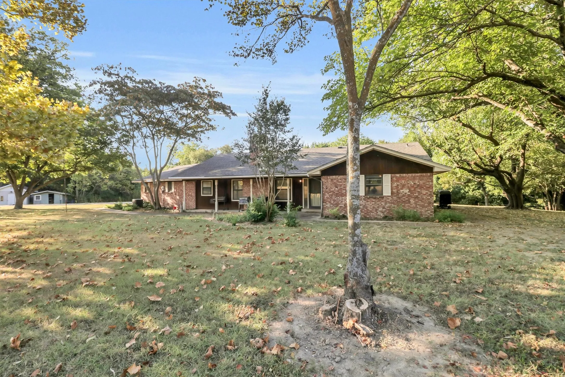 Brick exterior with a covered front porch and mature trees