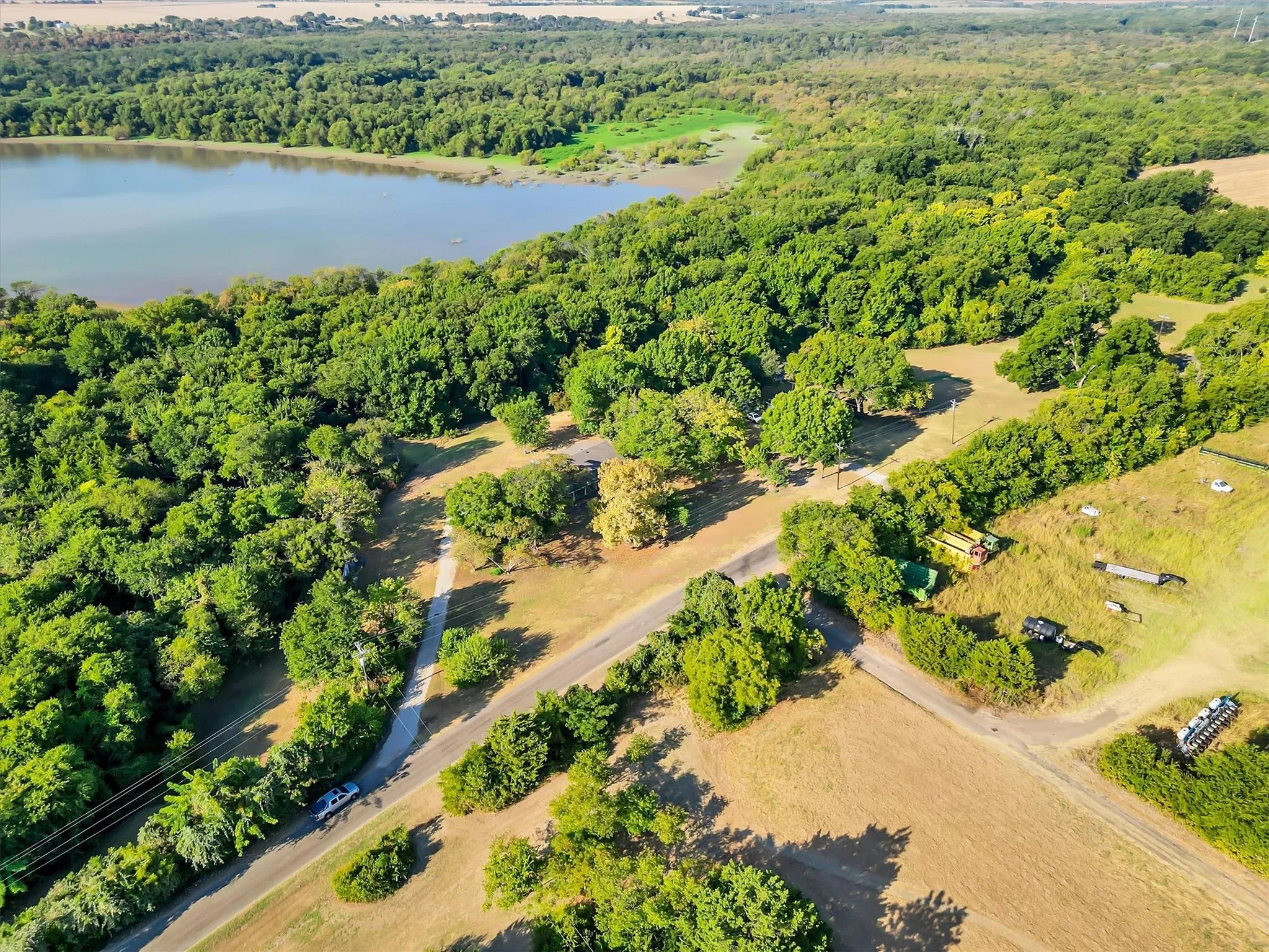 Expansive natural landscape with a large body of water, extensive tree coverage, and an unpaved road