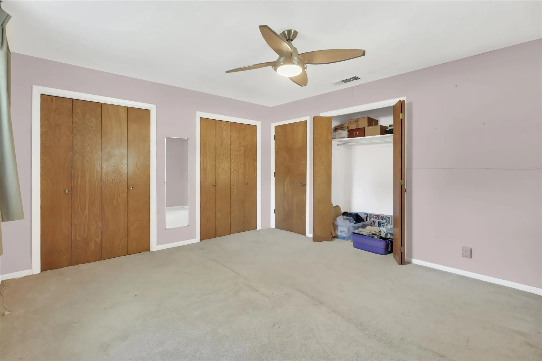 Integrated ceiling fan with lighting, multiple wood-panel closet doors, and recessed closet shelving